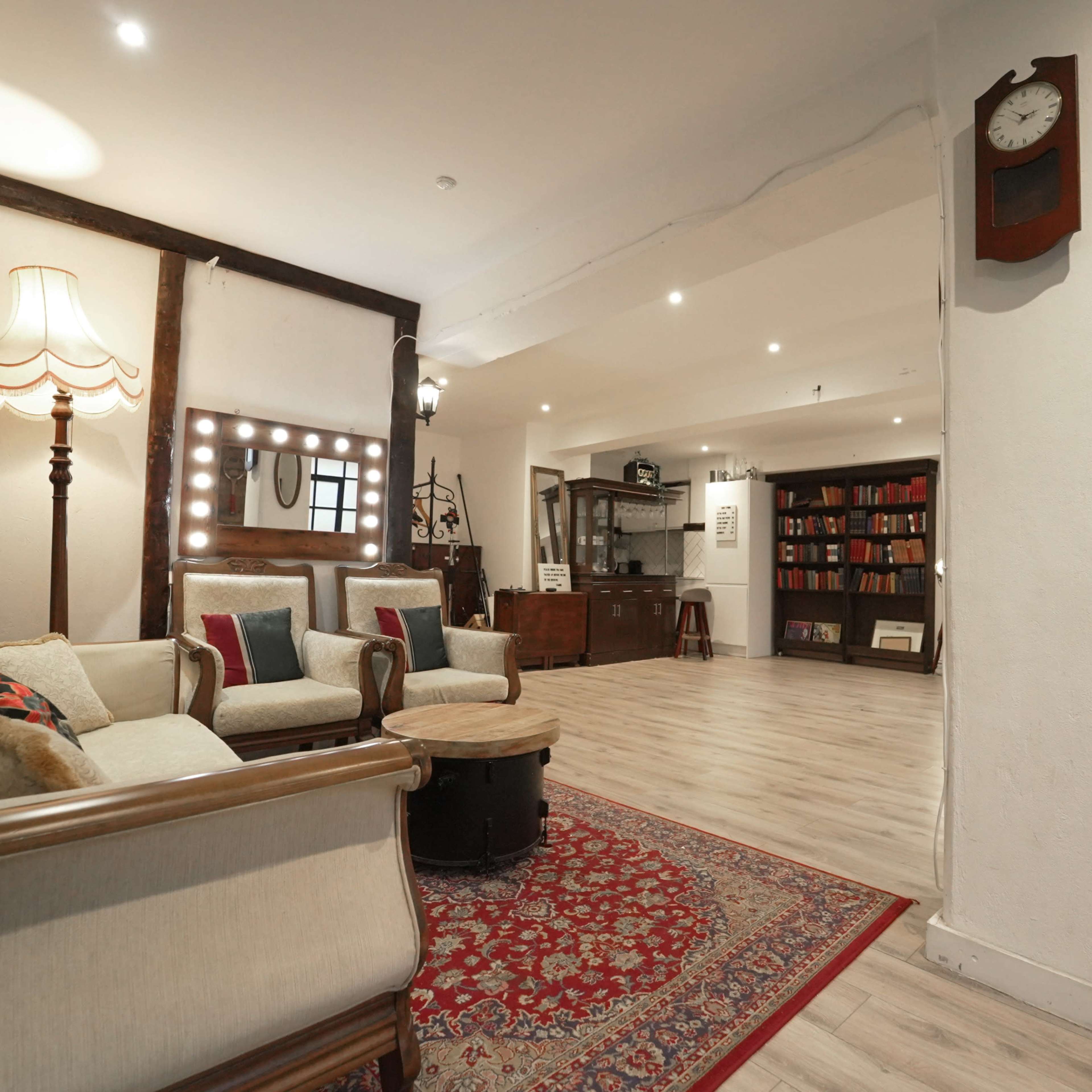 A spacious room with a vintage seating area, a large bookshelf filled with books, and warm lighting.