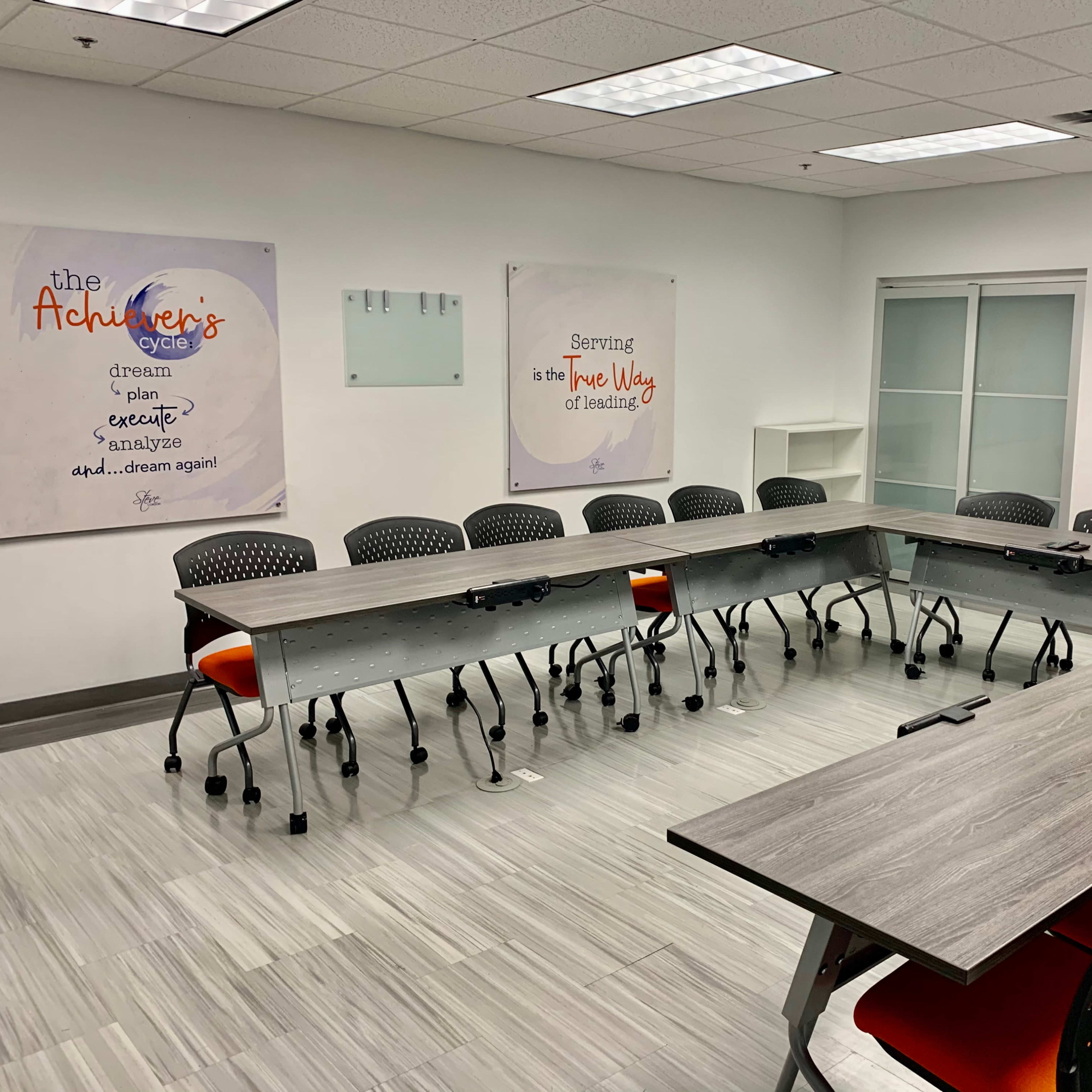 A modern conference room with a long, oval table surrounded by black chairs and motivational posters on the walls.