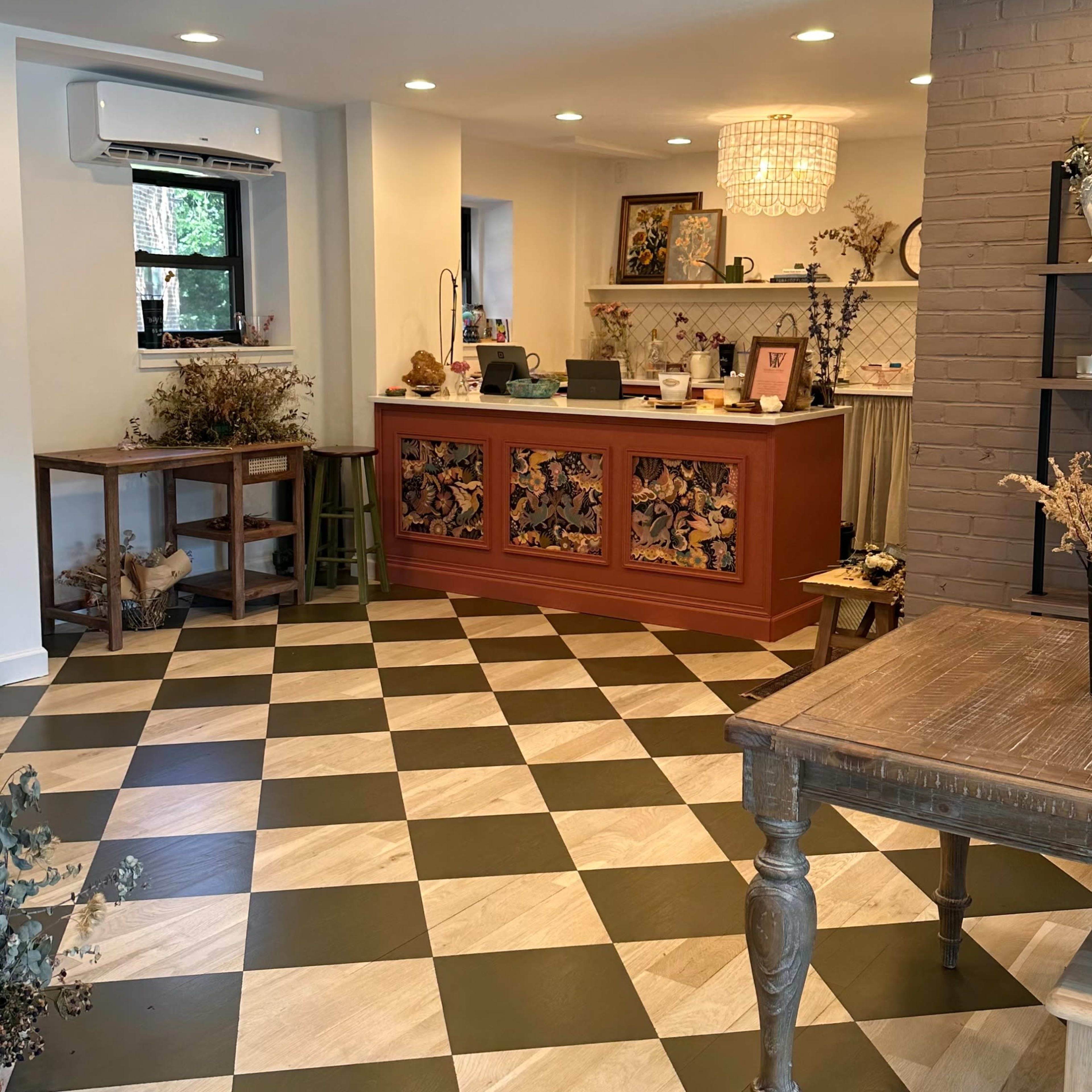 A well-lit interior space with a checkered floor, a reception desk featuring decorative panels, and various furniture and decor items arranged around the room.