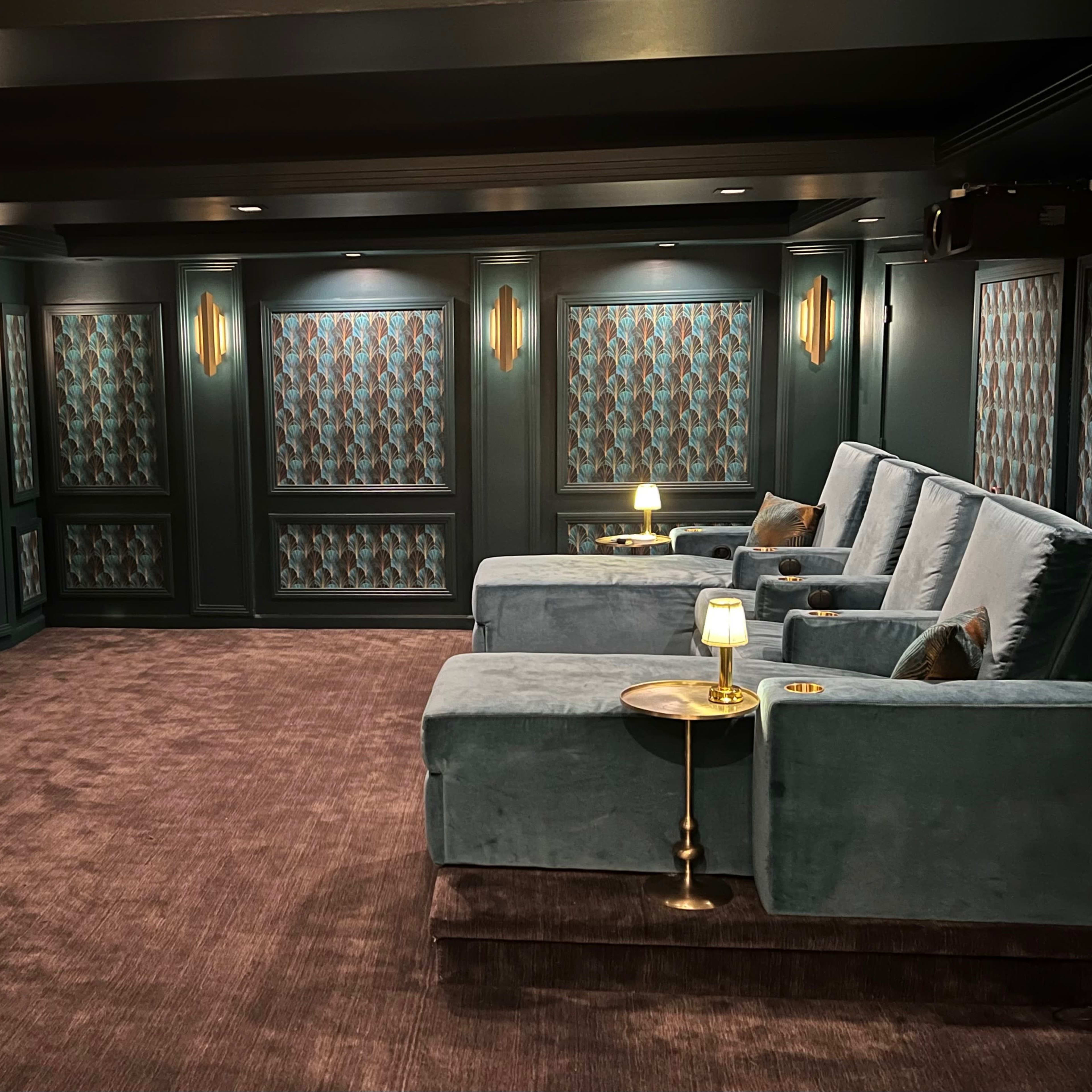 A home theater with plush seating, a large screen, and decorative wall panels.
