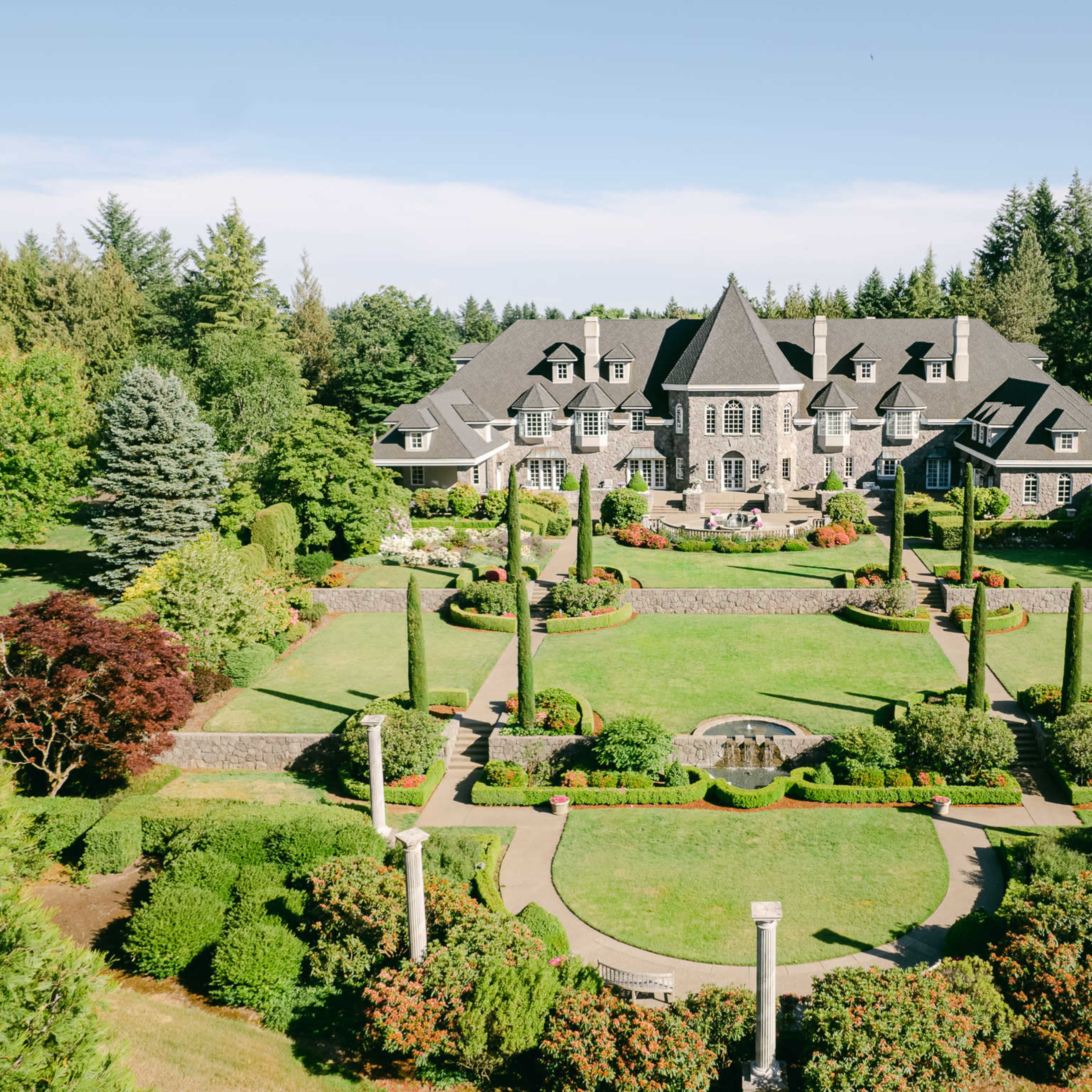 A large mansion surrounded by meticulously landscaped gardens and trees is visible in the image.