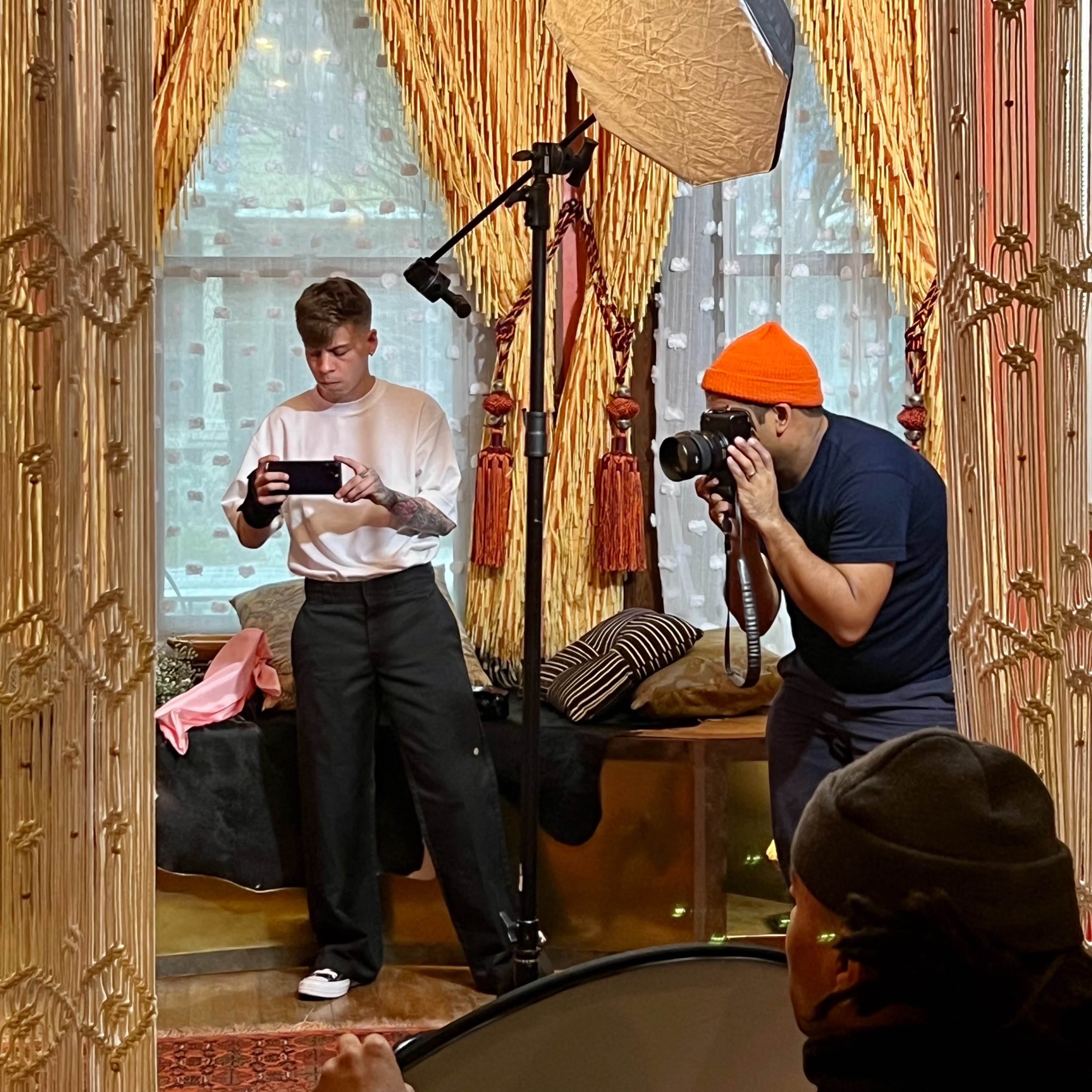 A photographer captures a model posing in front of a mirror in a decorated indoor space.