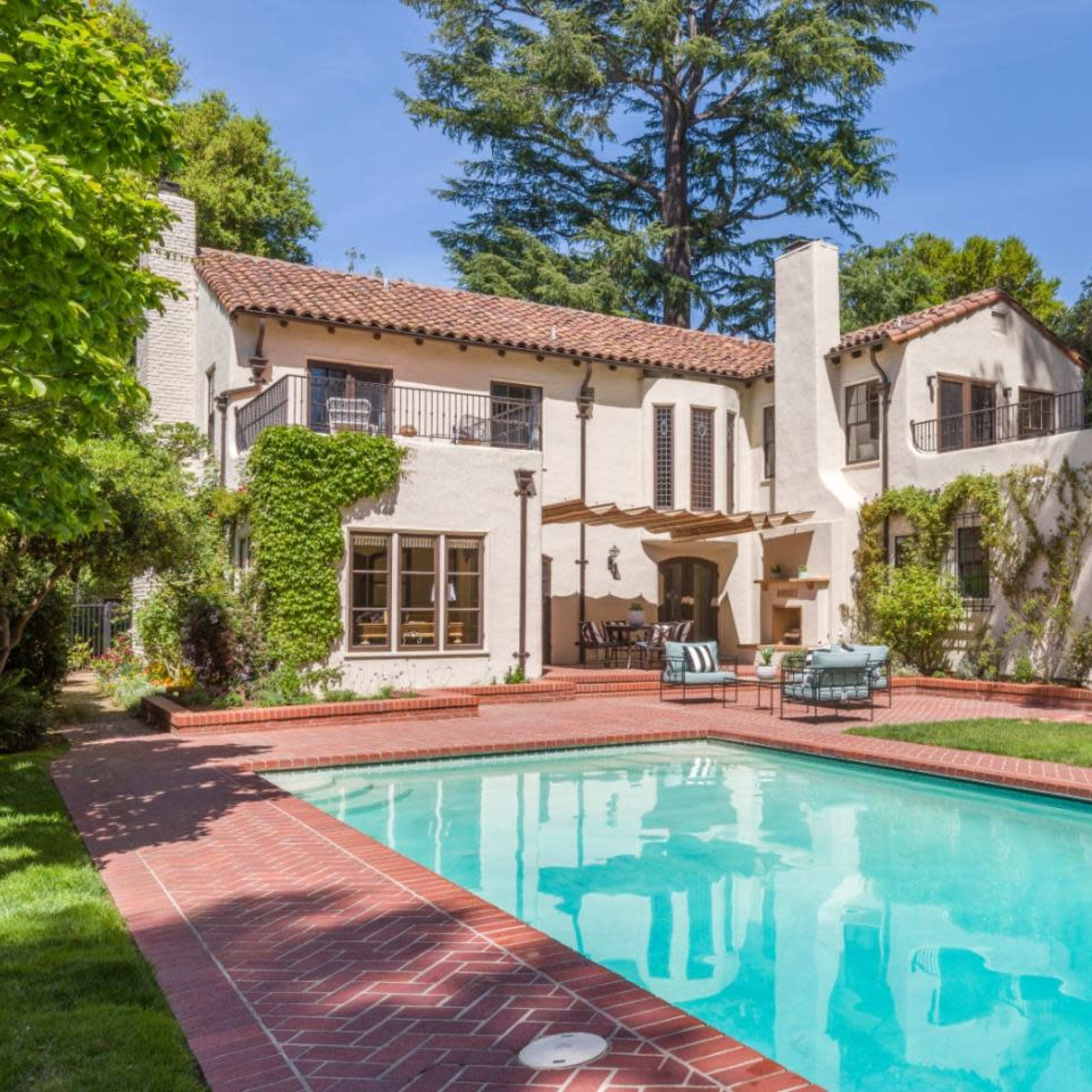 A two-story, Mediterranean-style house with a swimming pool and landscaped grounds.