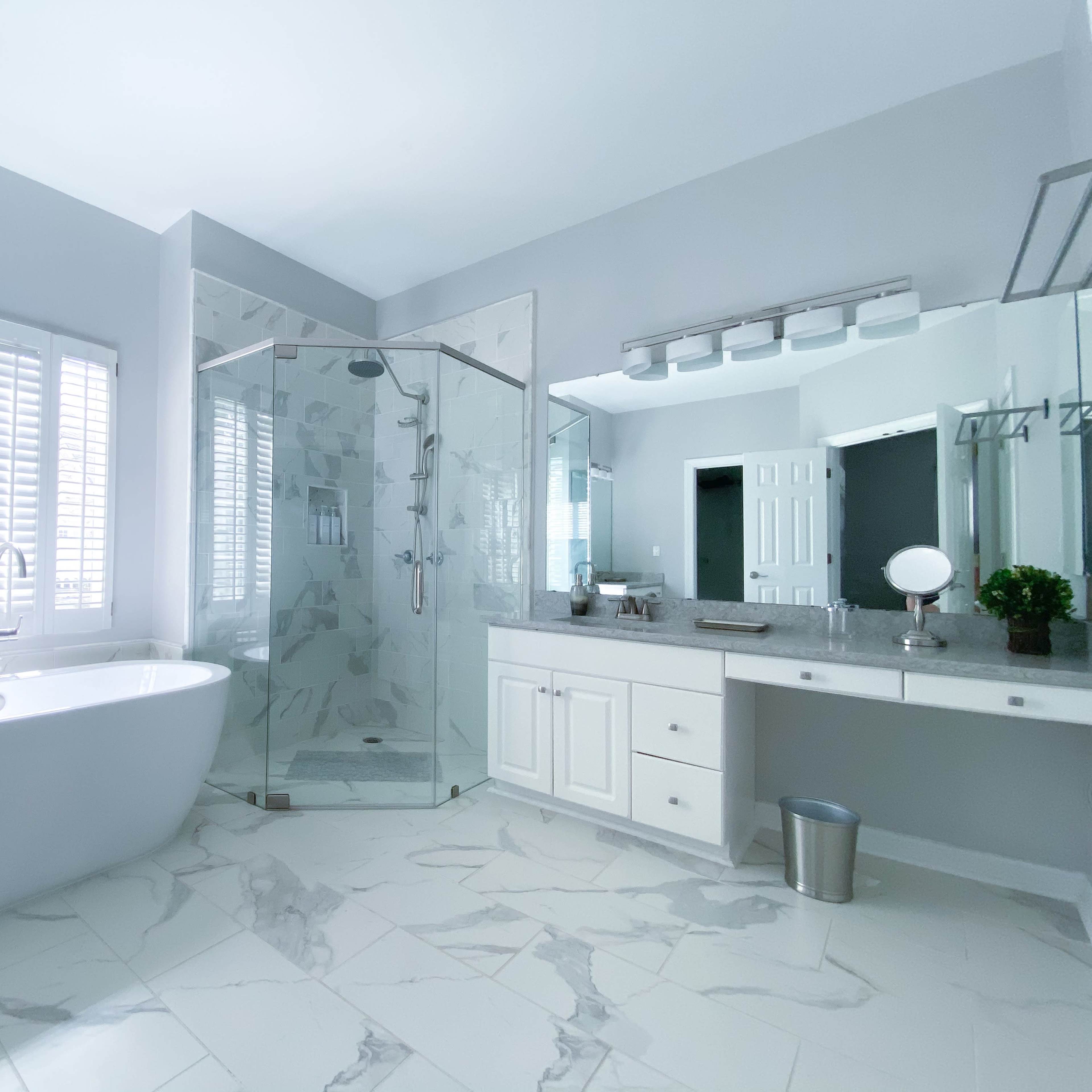 A modern bathroom featuring a freestanding bathtub, a glass-enclosed shower, and dual sinks with a large mirror.