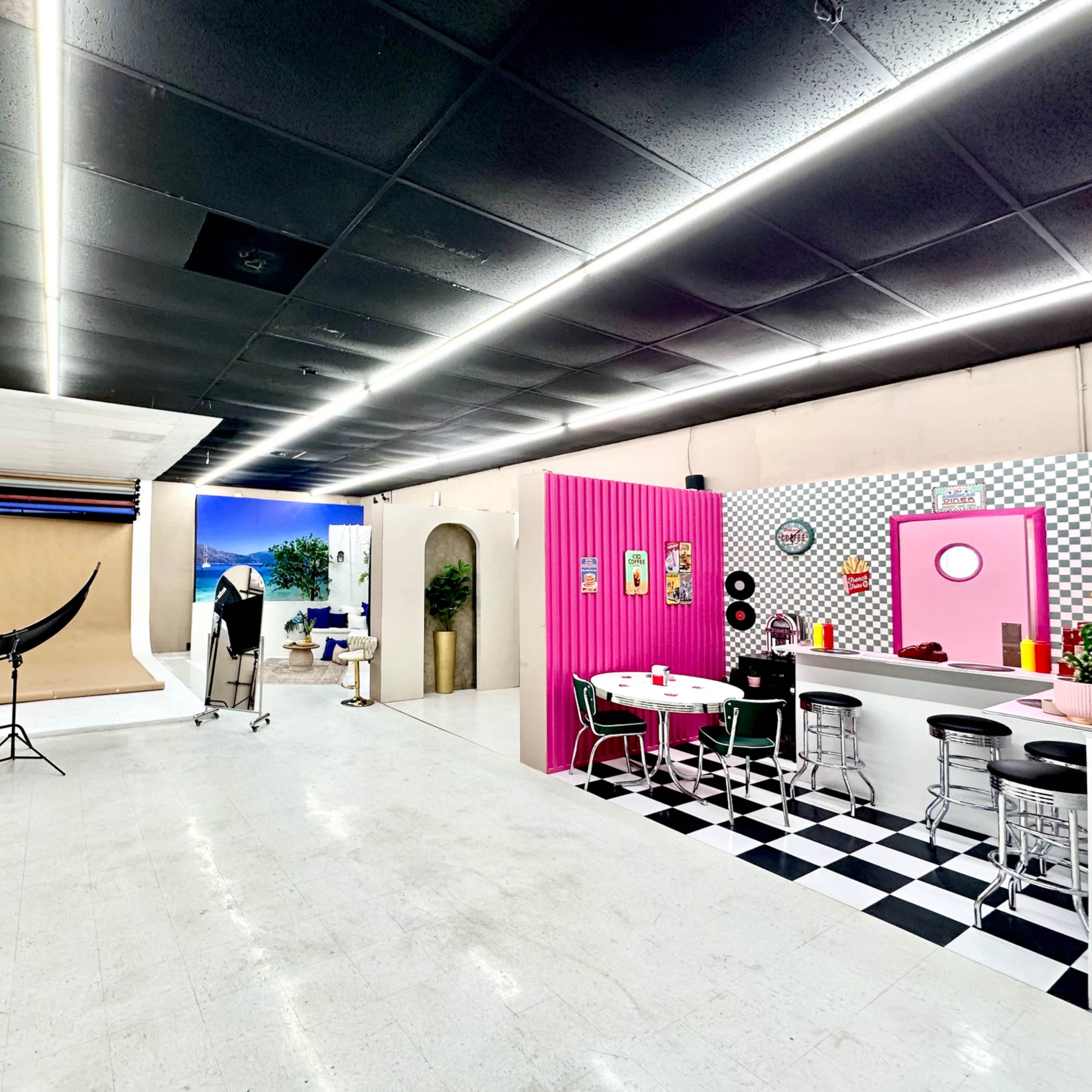 A photography studio with various setup areas, including a backdrop, lighting equipment, and a section designed like a diner.
