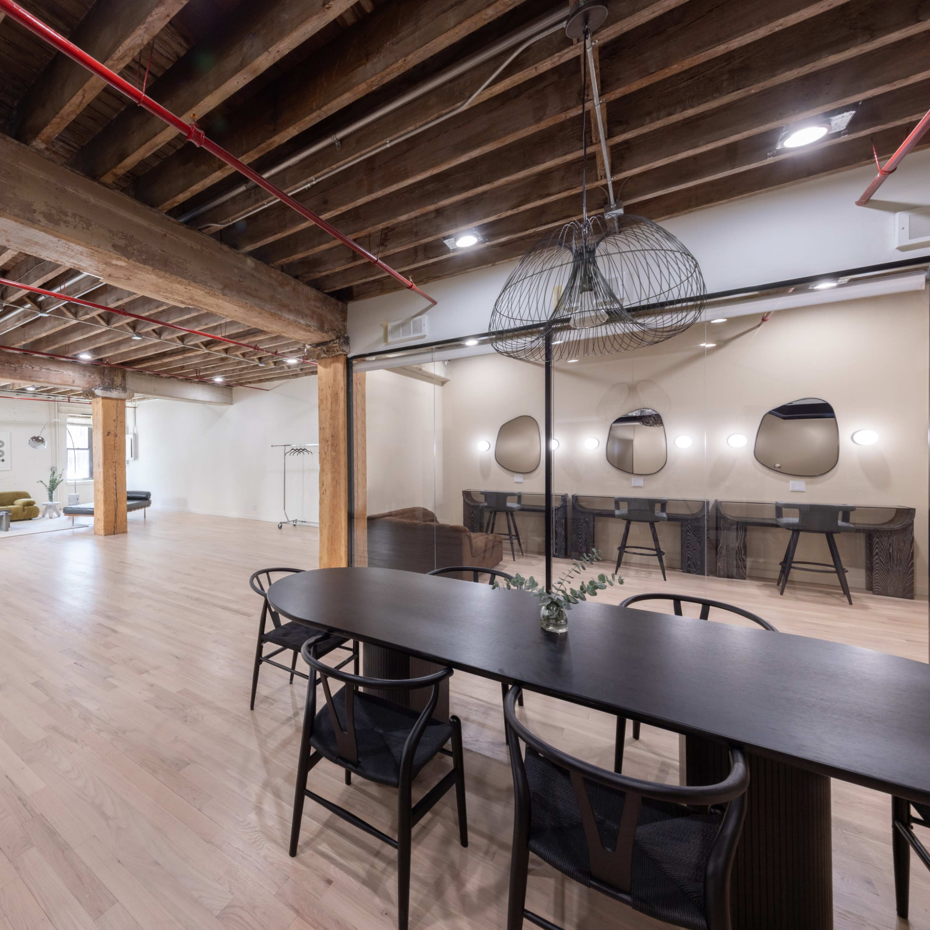 A spacious, modern interior featuring wooden beams, a dining table, and a seating area with plush furniture.