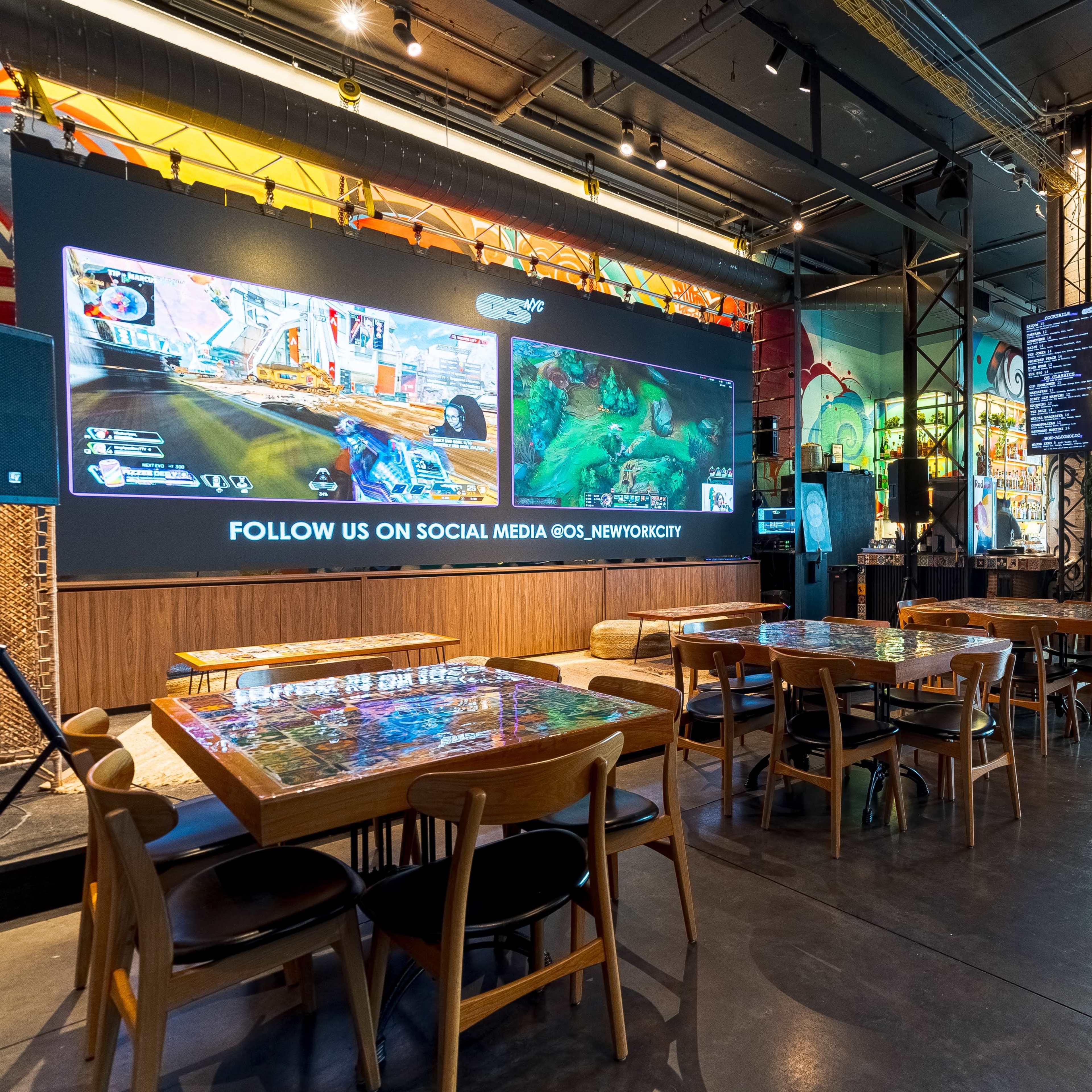 A modern dining space with large screens displaying gaming content and tables arranged for customers.