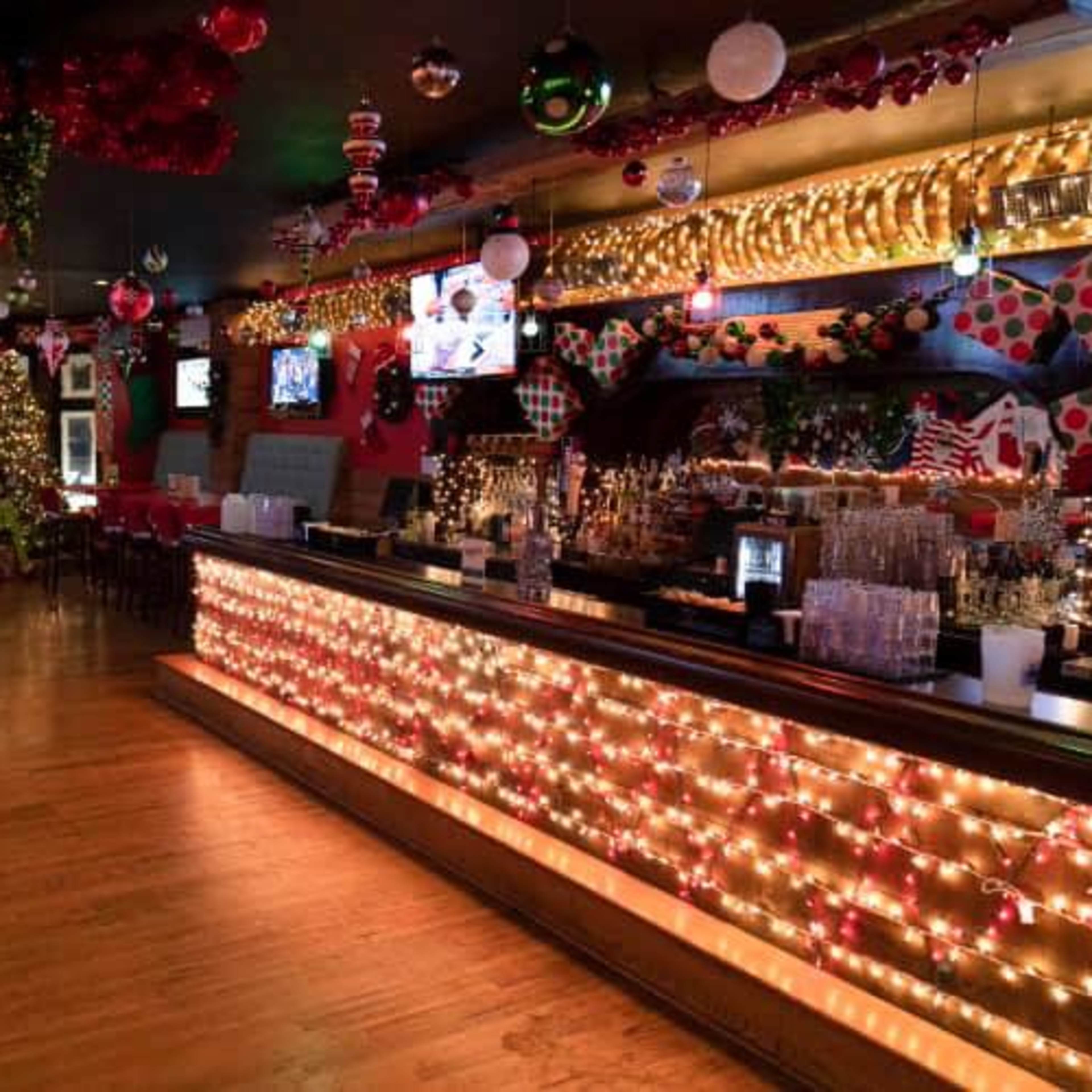 A festive bar decorated with holiday lights, ornaments, and a decorated Christmas tree.