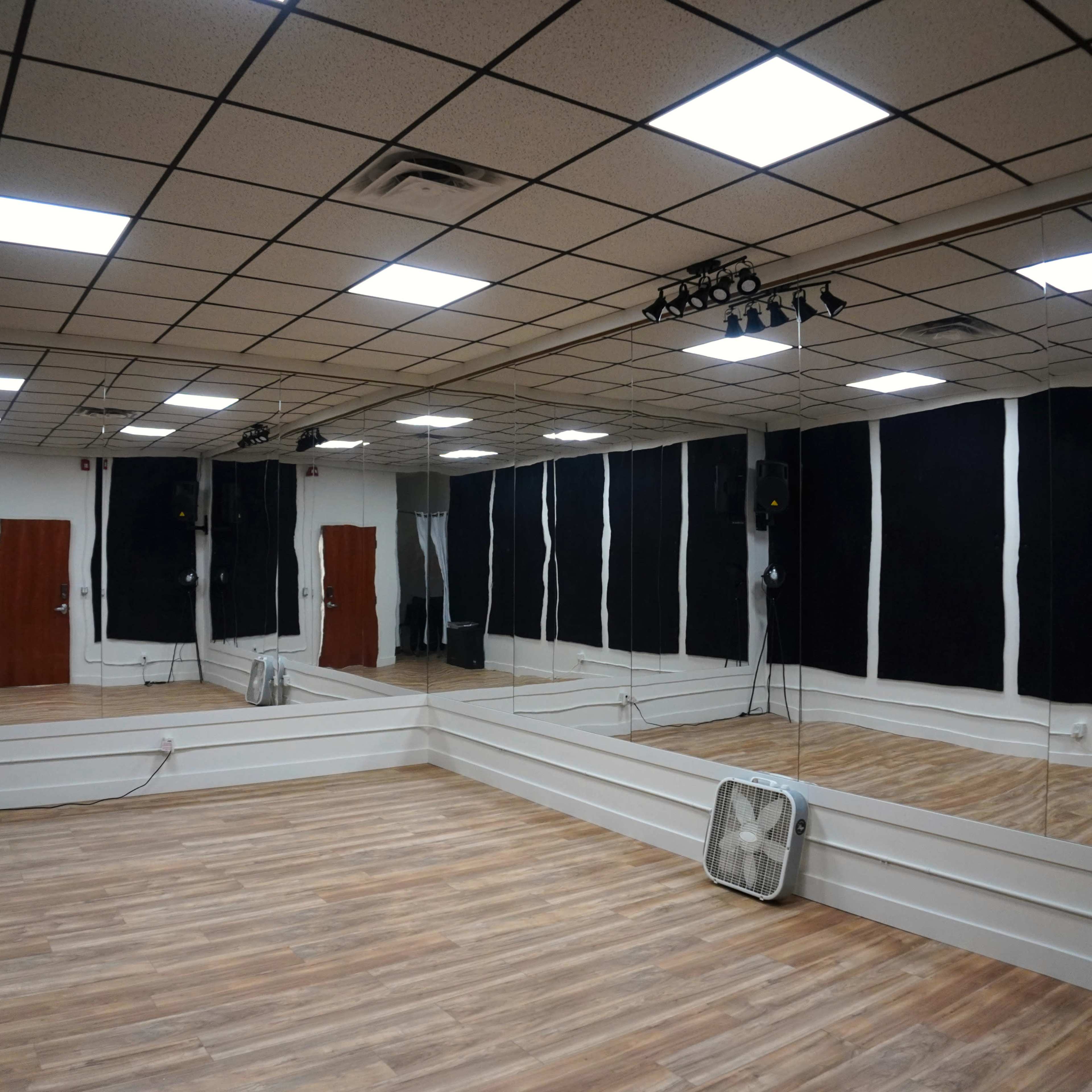 A dance studio features mirrored walls, wooden flooring, and black soundproof panels.