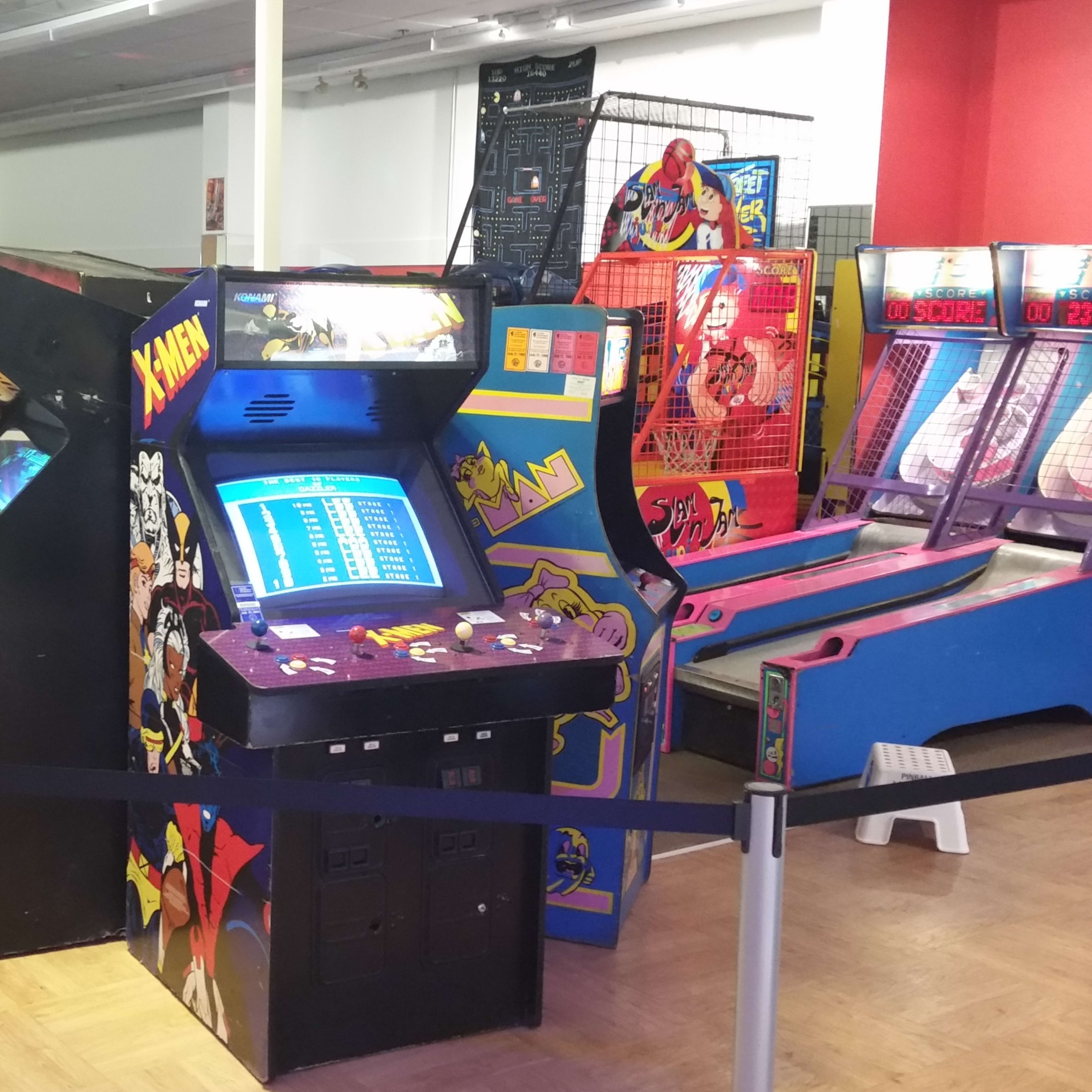 A row of vintage arcade game machines in a brightly lit game room.