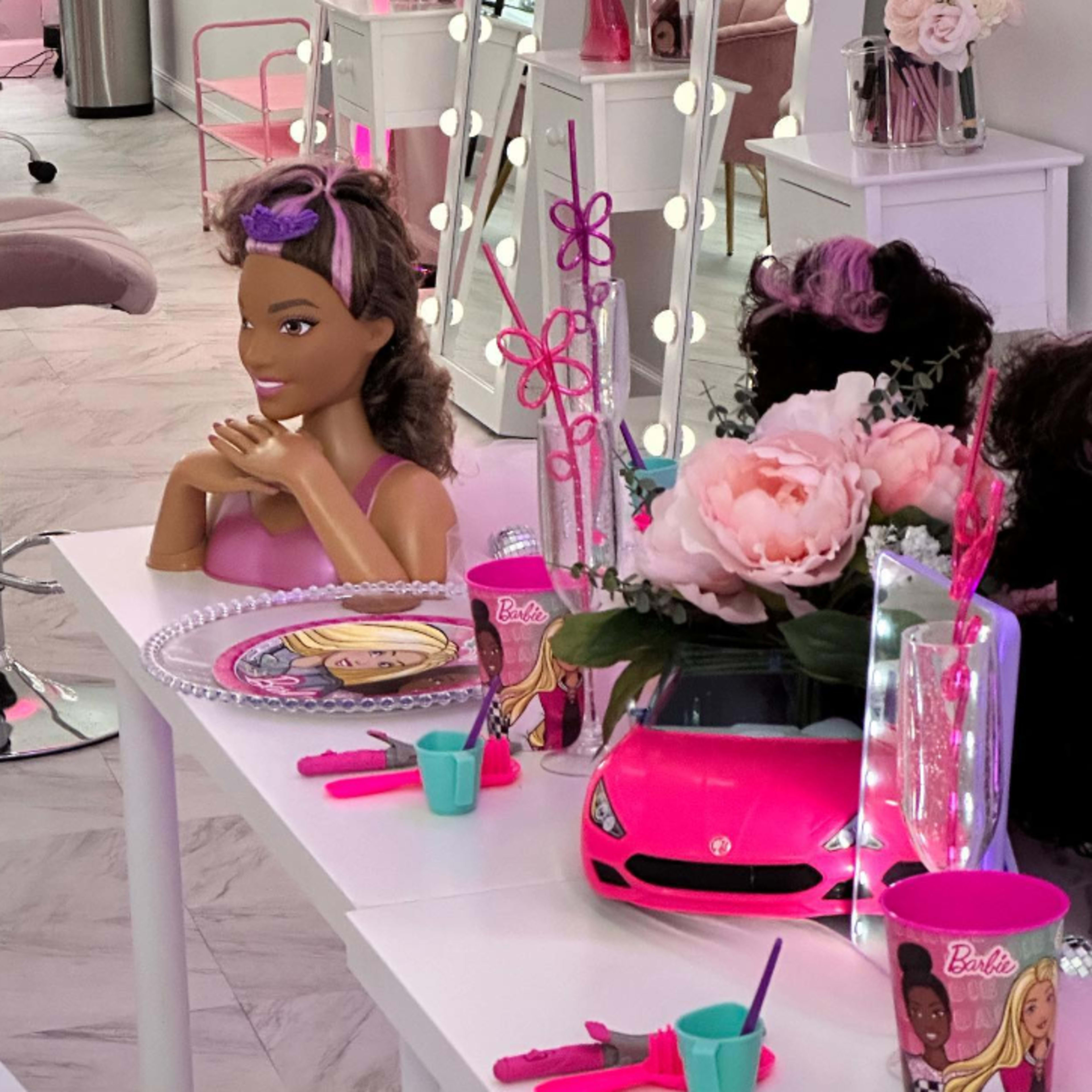 The scene features a brightly decorated room with a table set for a themed party, including a Barbie doll, pink decorations, and various accessories.