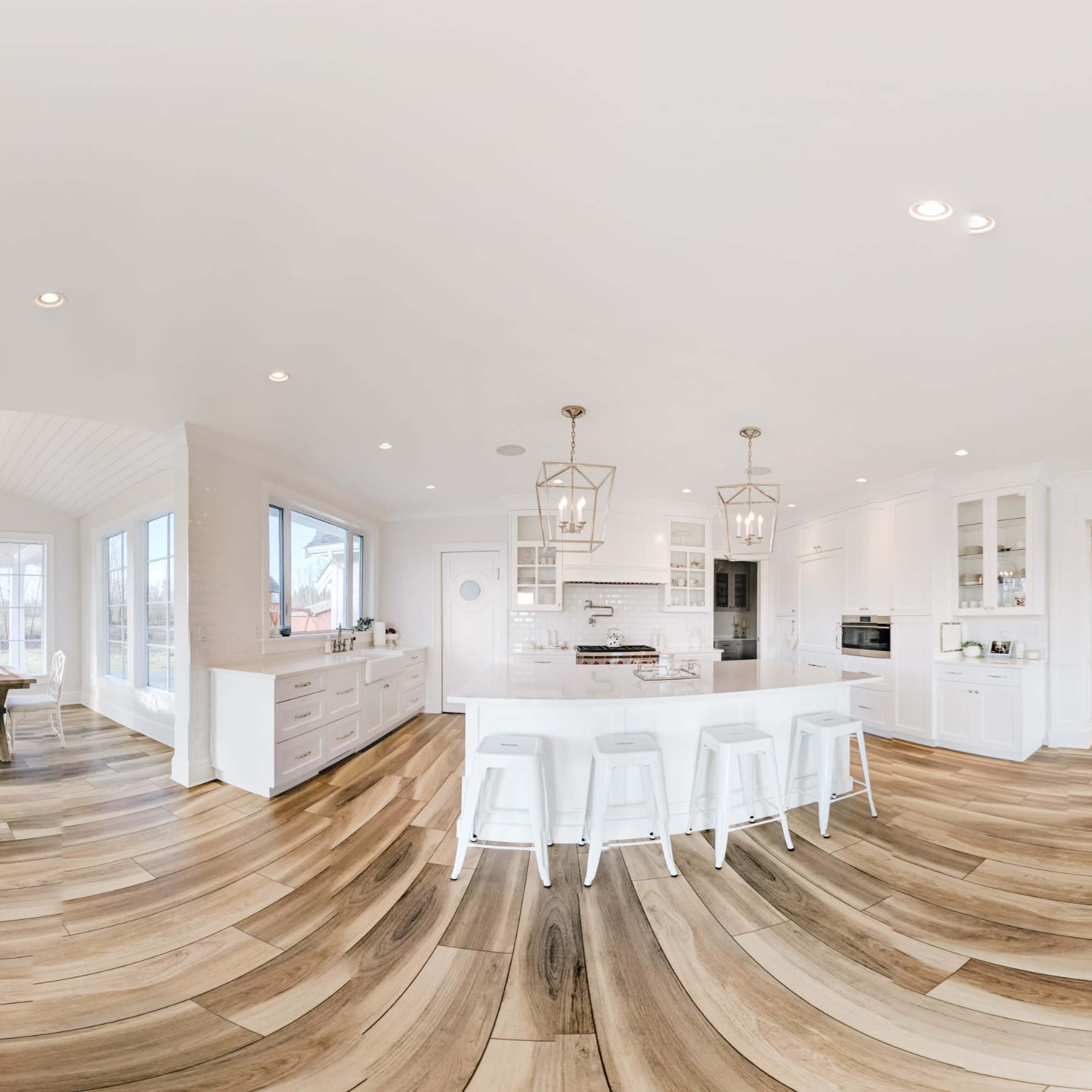 A spacious, modern living area featuring a kitchen, dining area, and lounging space with large windows and wood flooring.