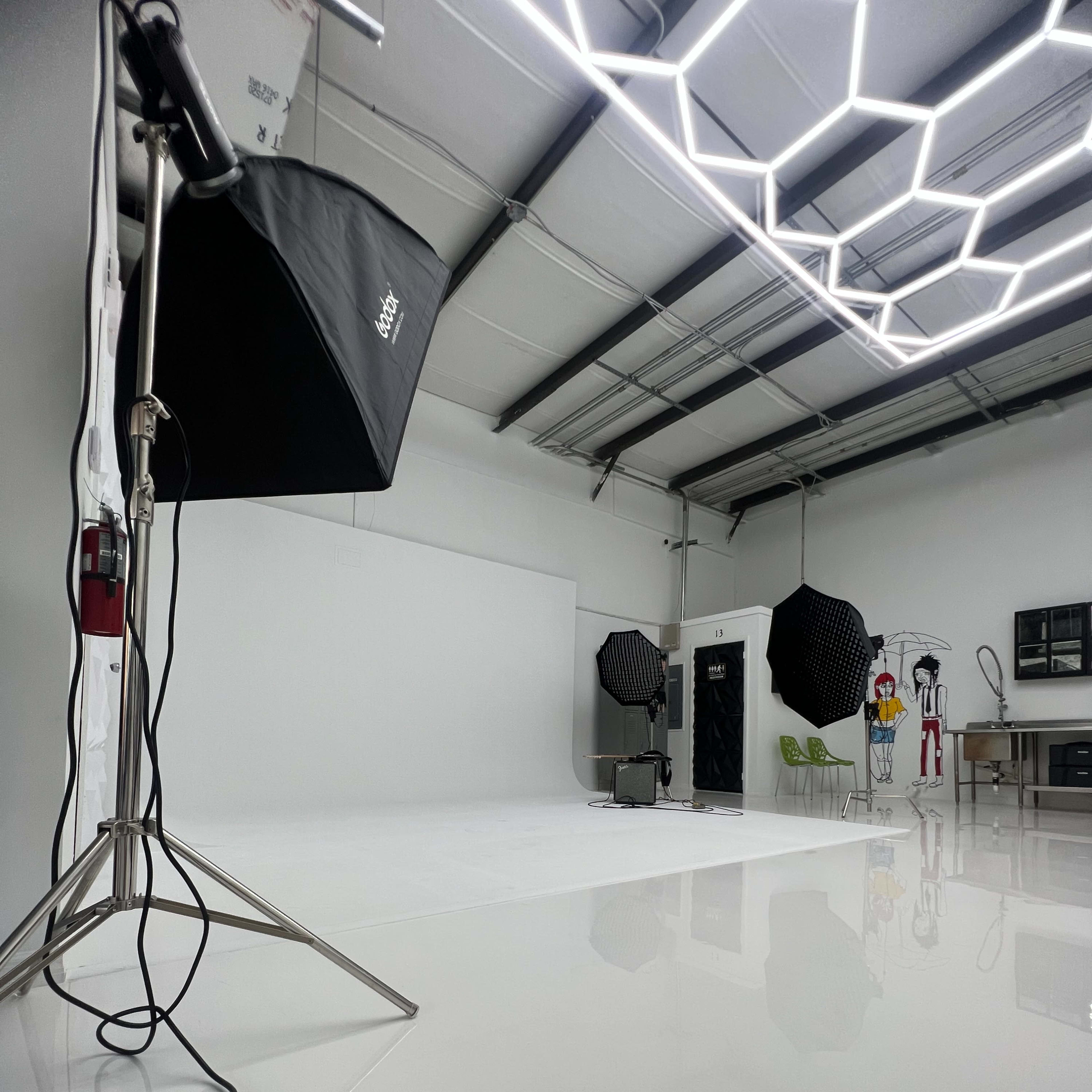 A photography studio equipped with lighting equipment, a white backdrop, and various props.