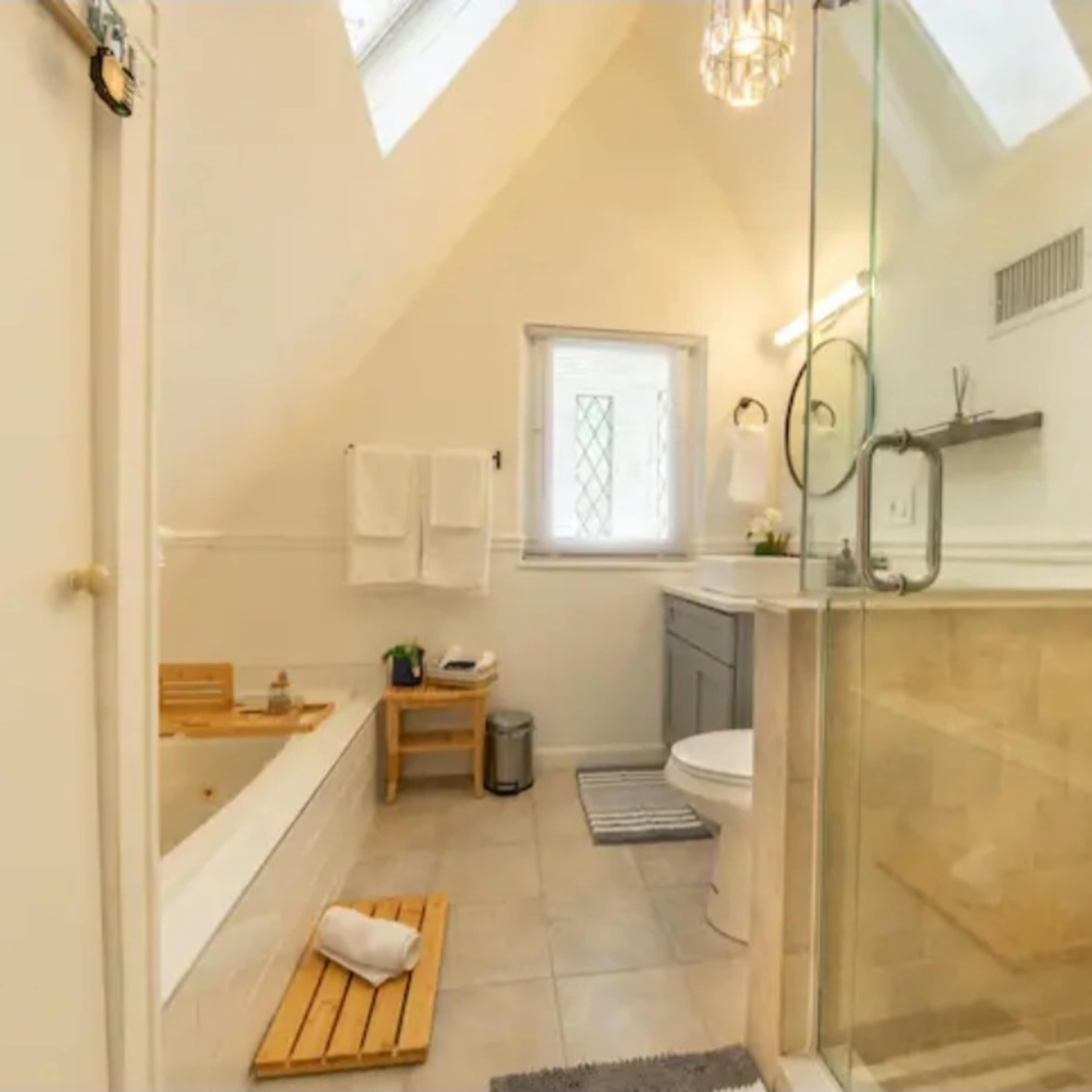 The bathroom features a bathtub, a glass shower, and a vanity with a sink in a bright, airy space.