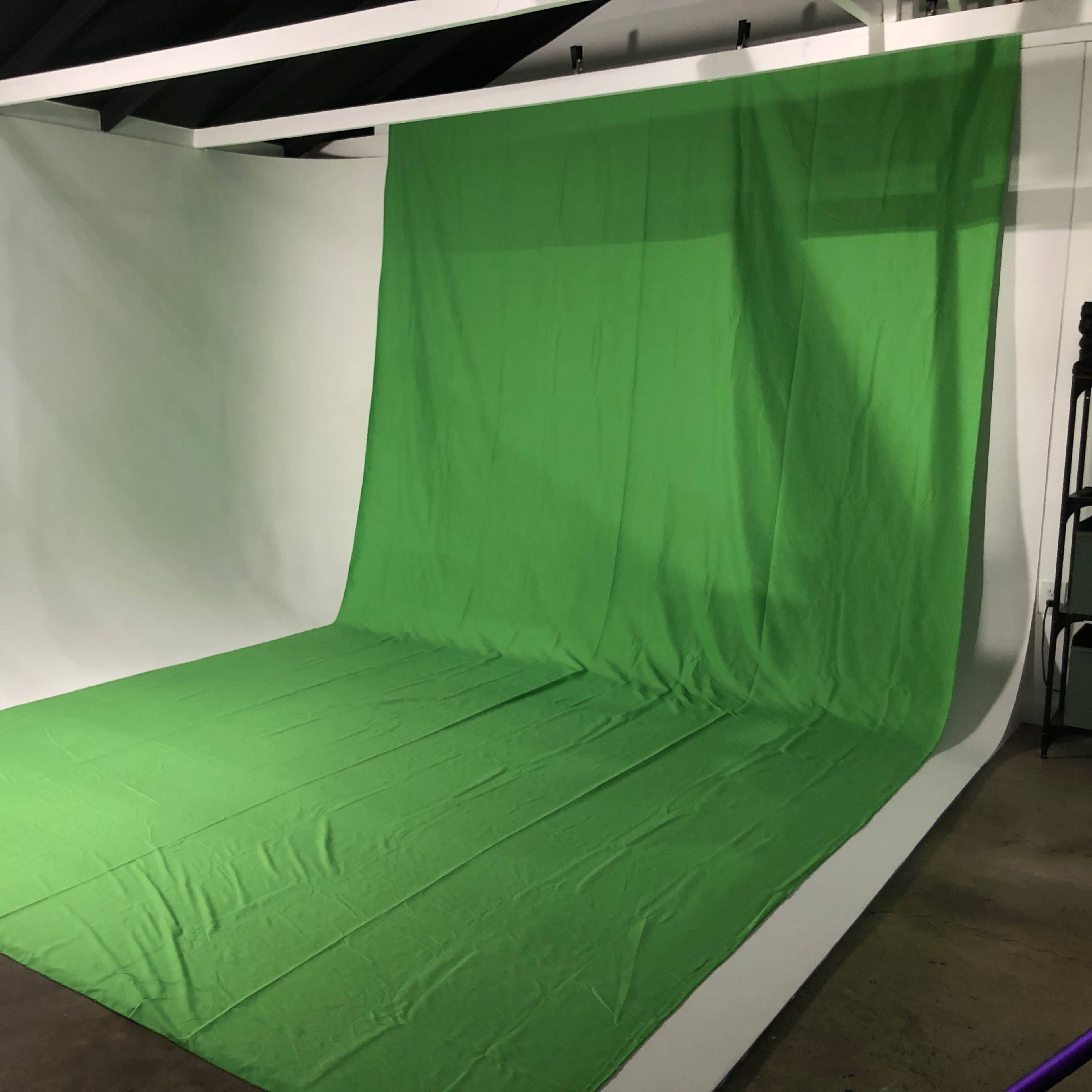 A photography studio with a large green backdrop and white walls.