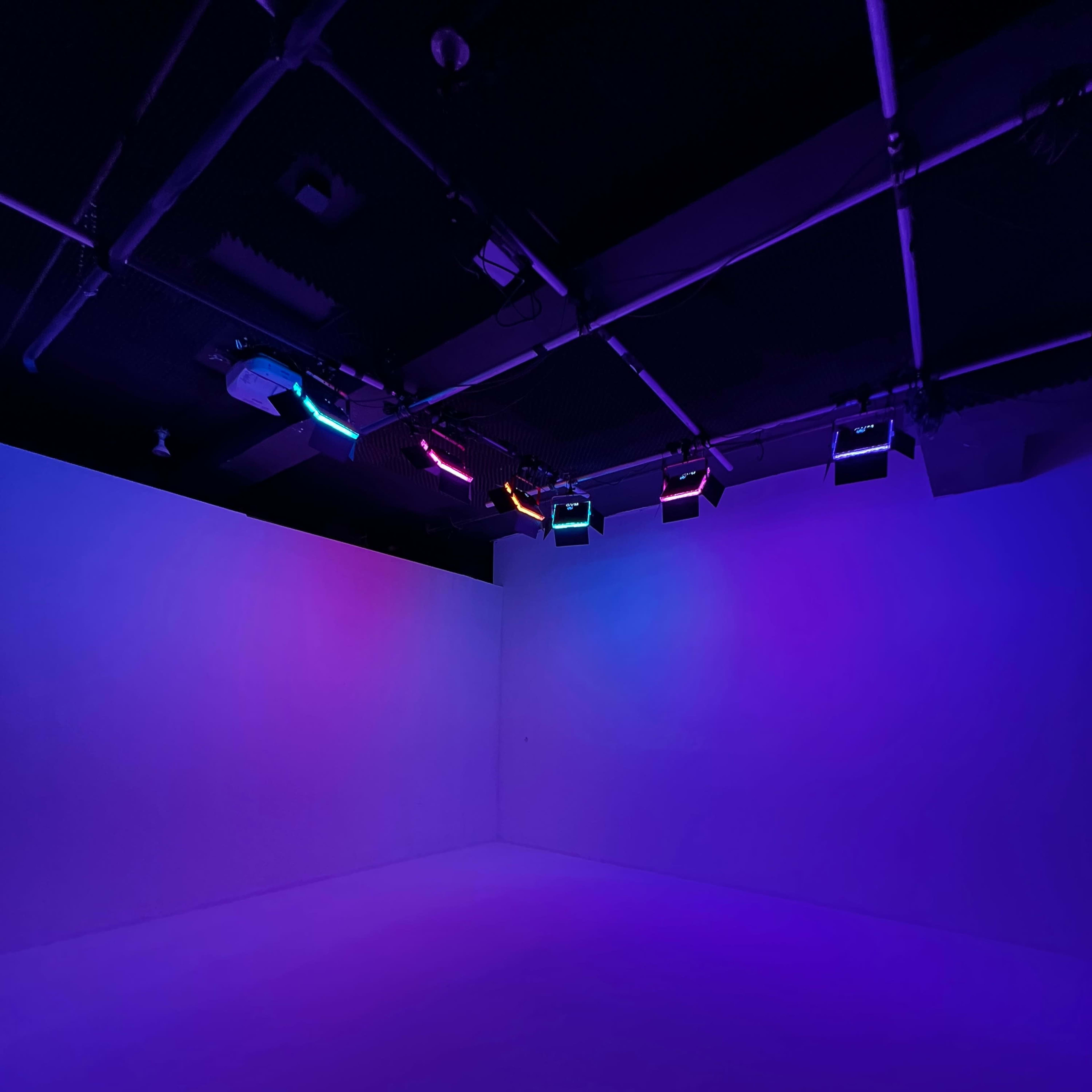 An empty room with purple and blue lighting from overhead fixtures.