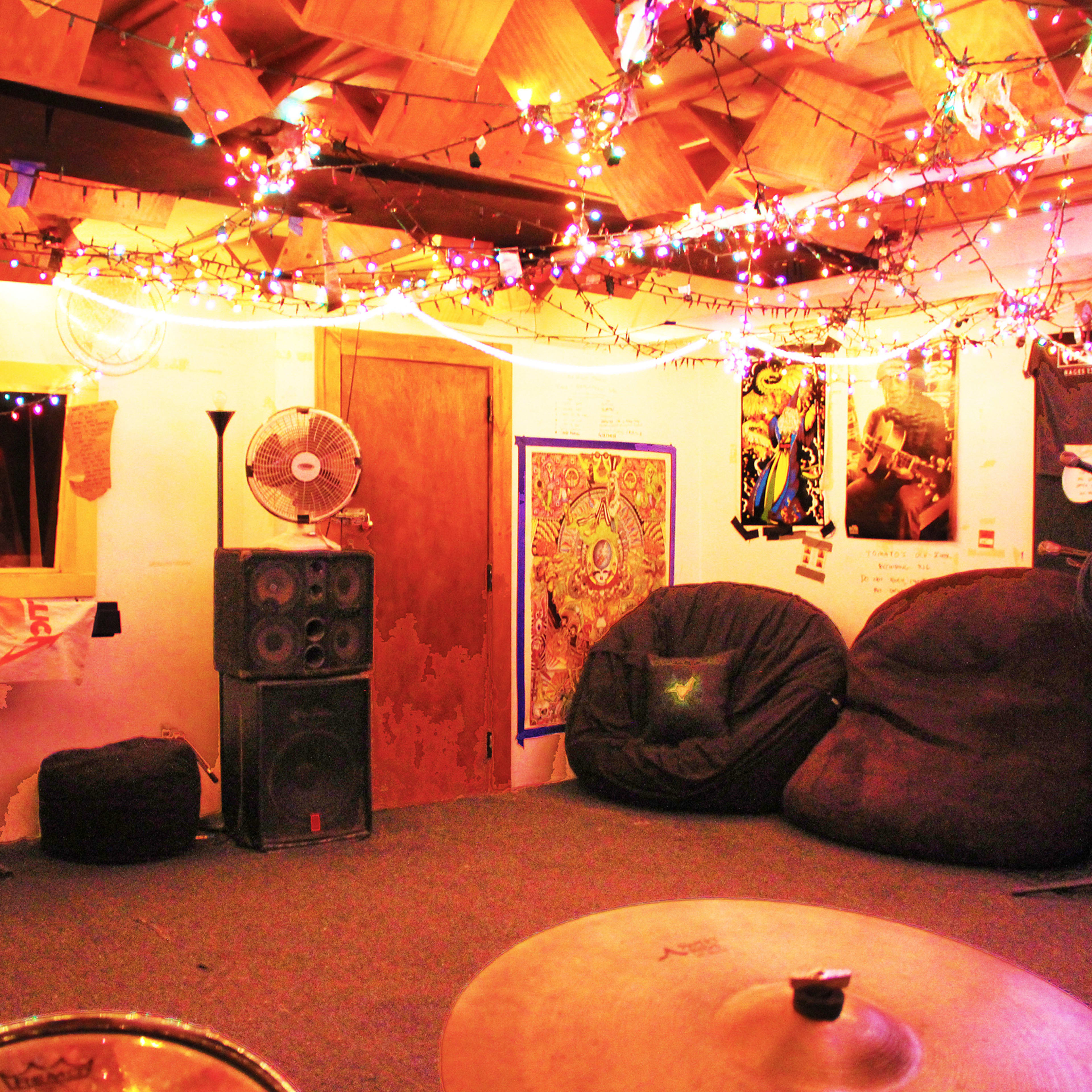 A decorated music practice room with colorful string lights, bean bag chairs, and musical equipment.