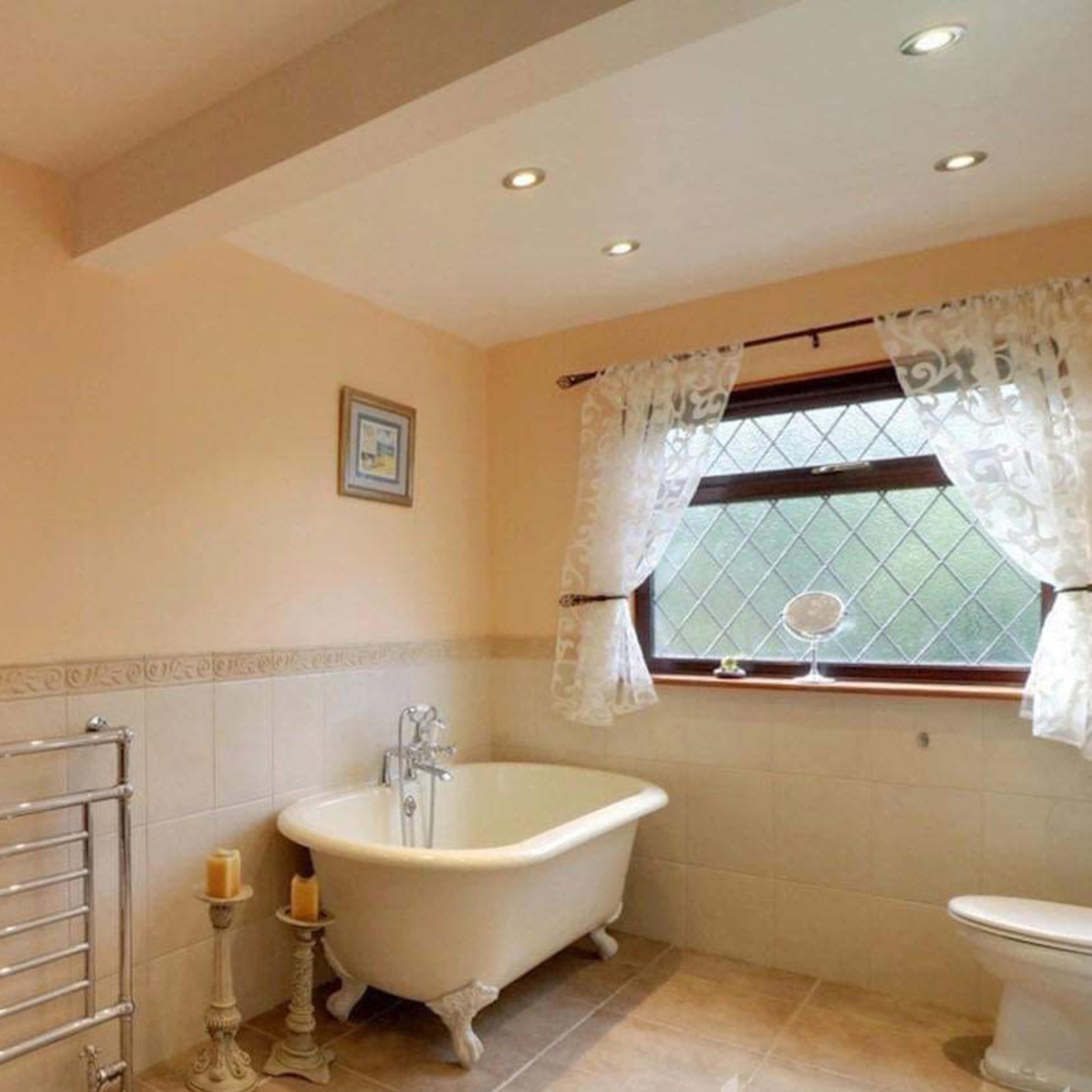 A bathroom featuring a freestanding bathtub, a wooden chest, and decorative framed artwork on the walls.
