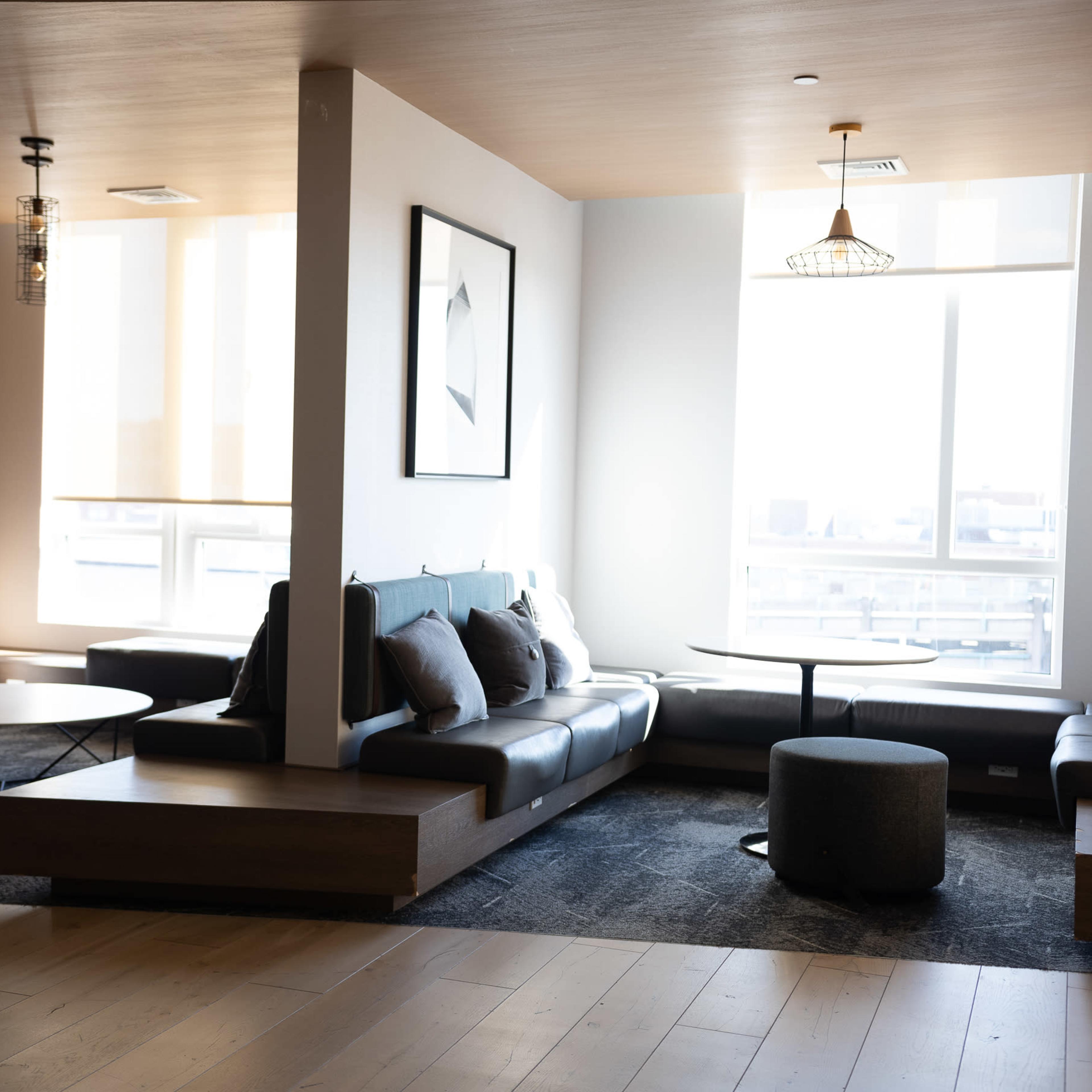 A modern lounge area with a sectional sofa, circular coffee table, and large windows letting in natural light.