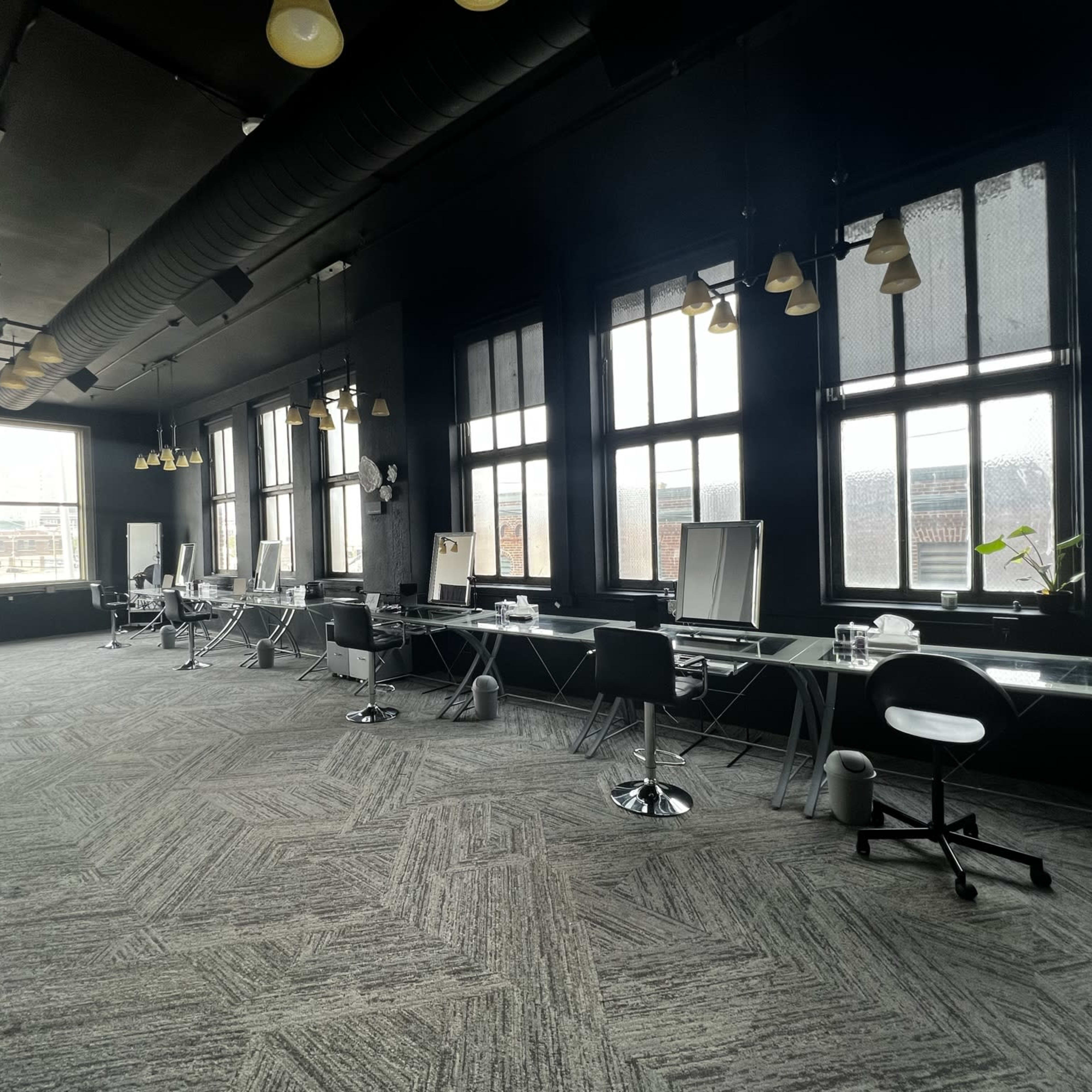A spacious, modern office interior with large windows, multiple workstations, and a minimalist design.