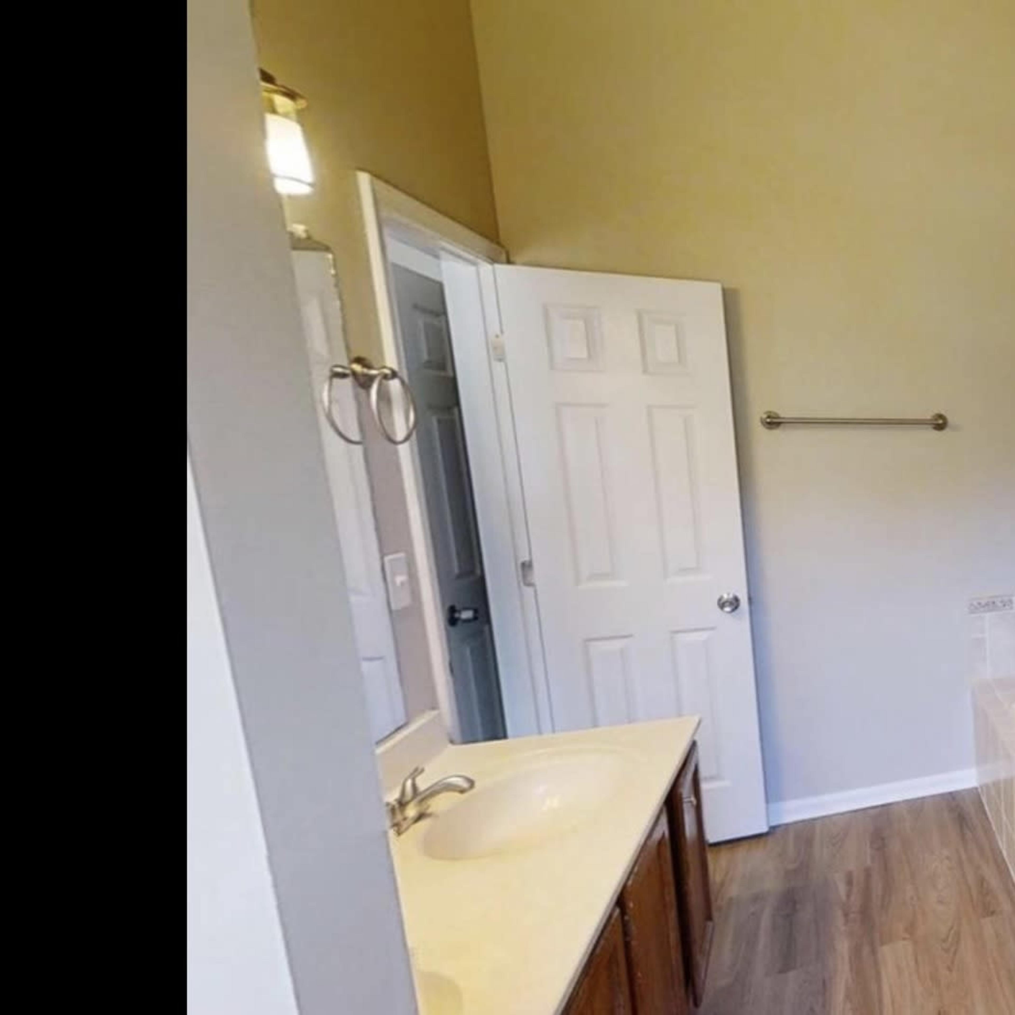 A bathroom featuring a glass shower, a bathtub, a double vanity with sinks, and a door leading to another room.
