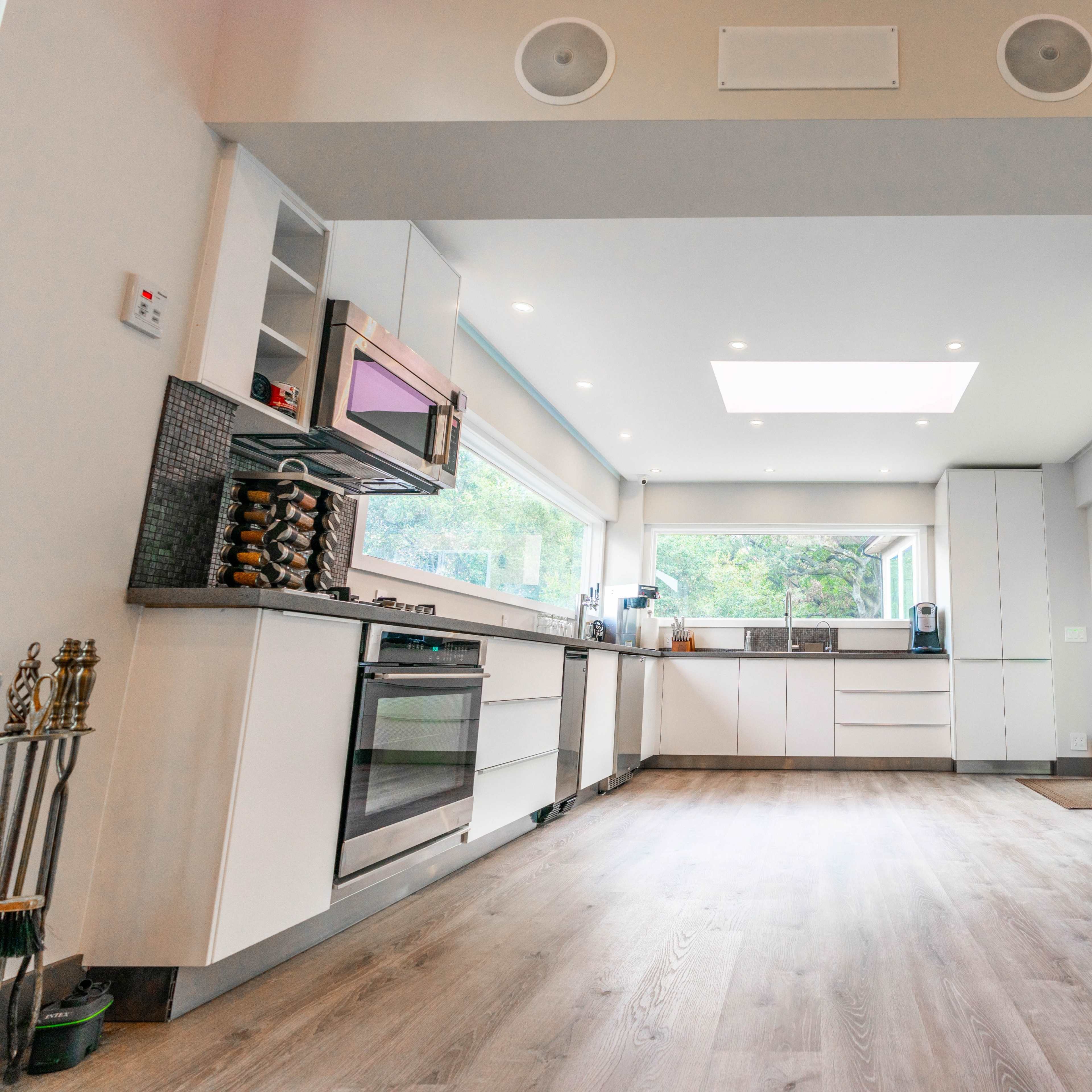 A modern kitchen with a large window, sleek cabinetry, and a fireplace on one side.
