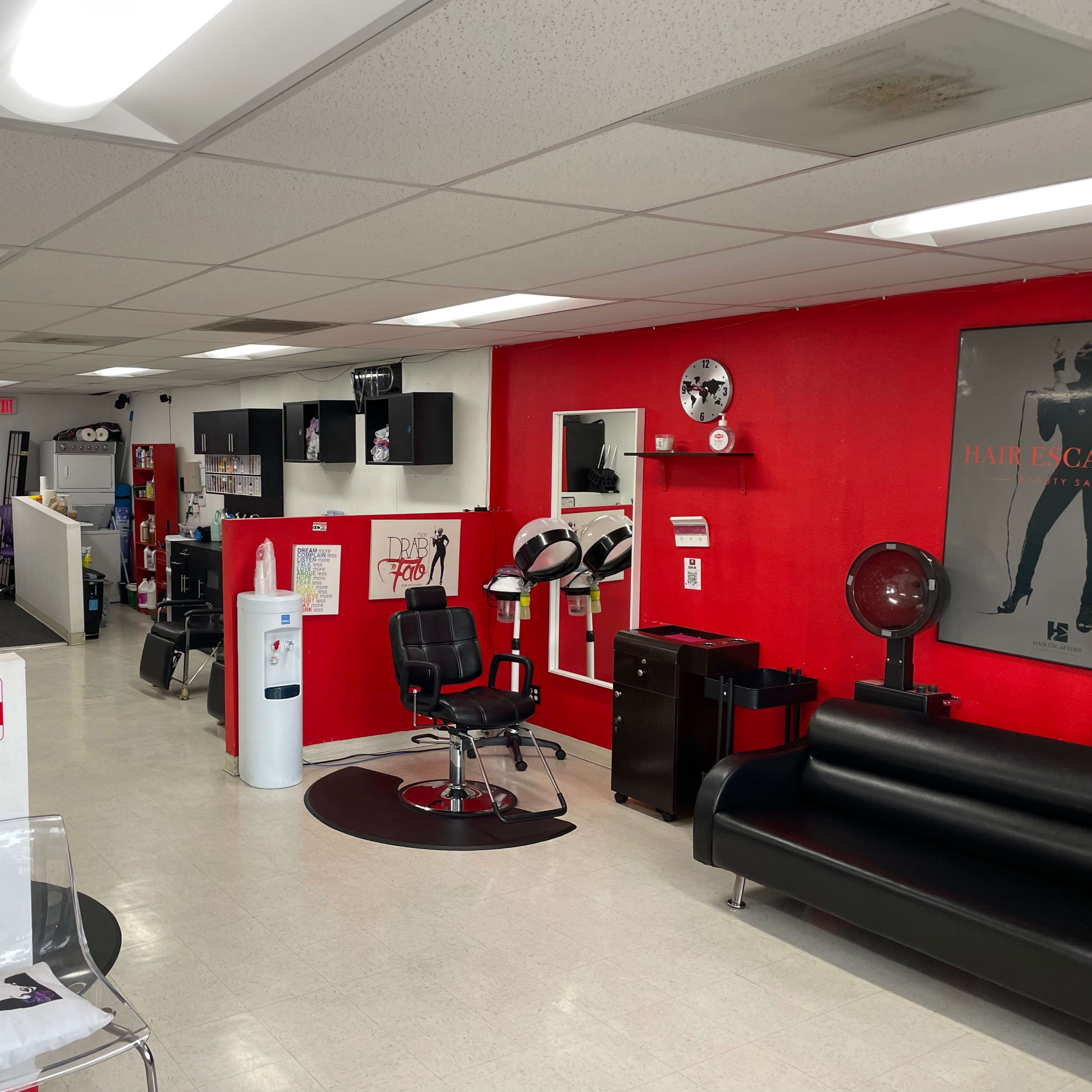 A brightly lit salon with black and red decor, featuring styling chairs, a reception area, and various hair care products on display.