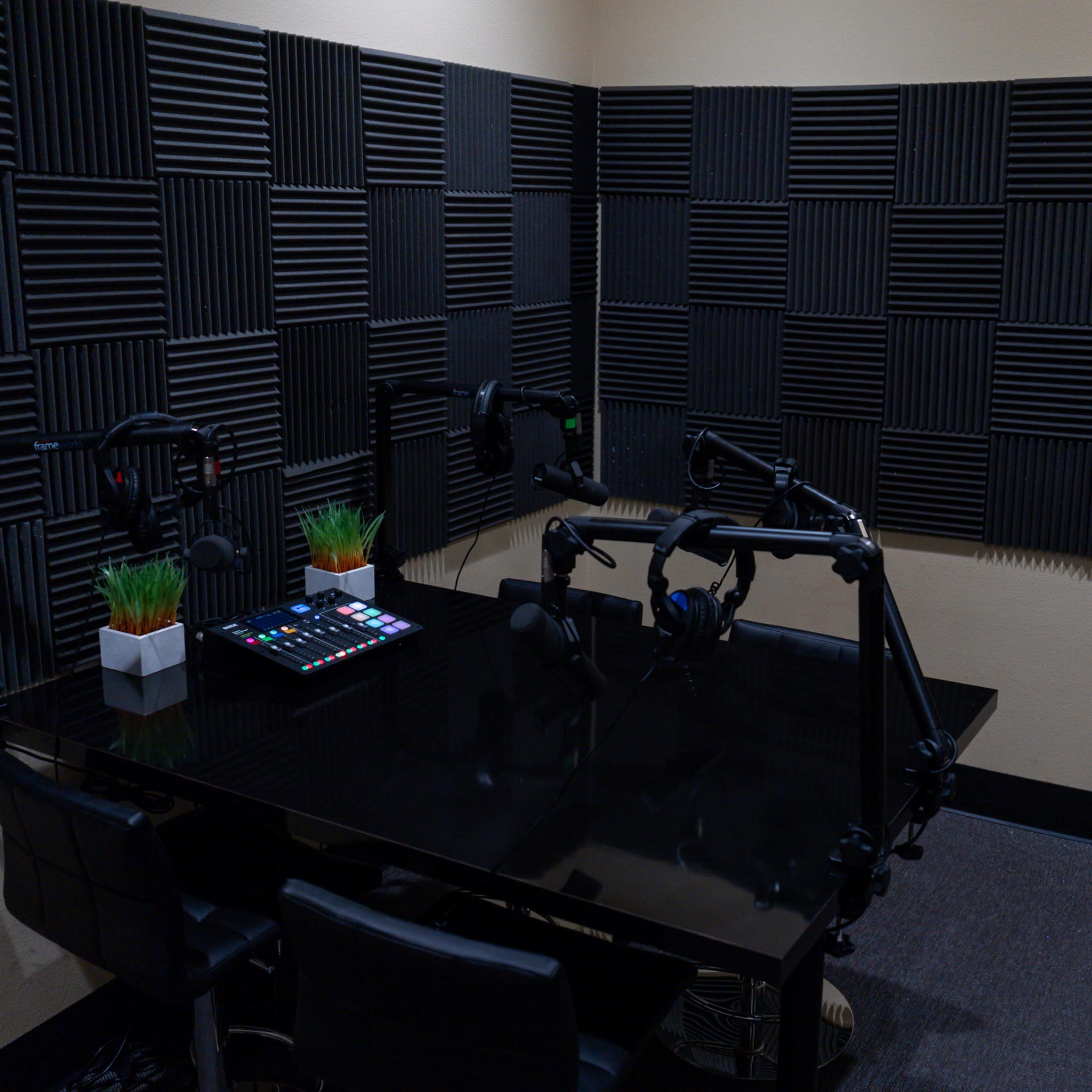 A soundproof recording studio with dark acoustic panels on the walls, a black table, and equipment for audio recording.
