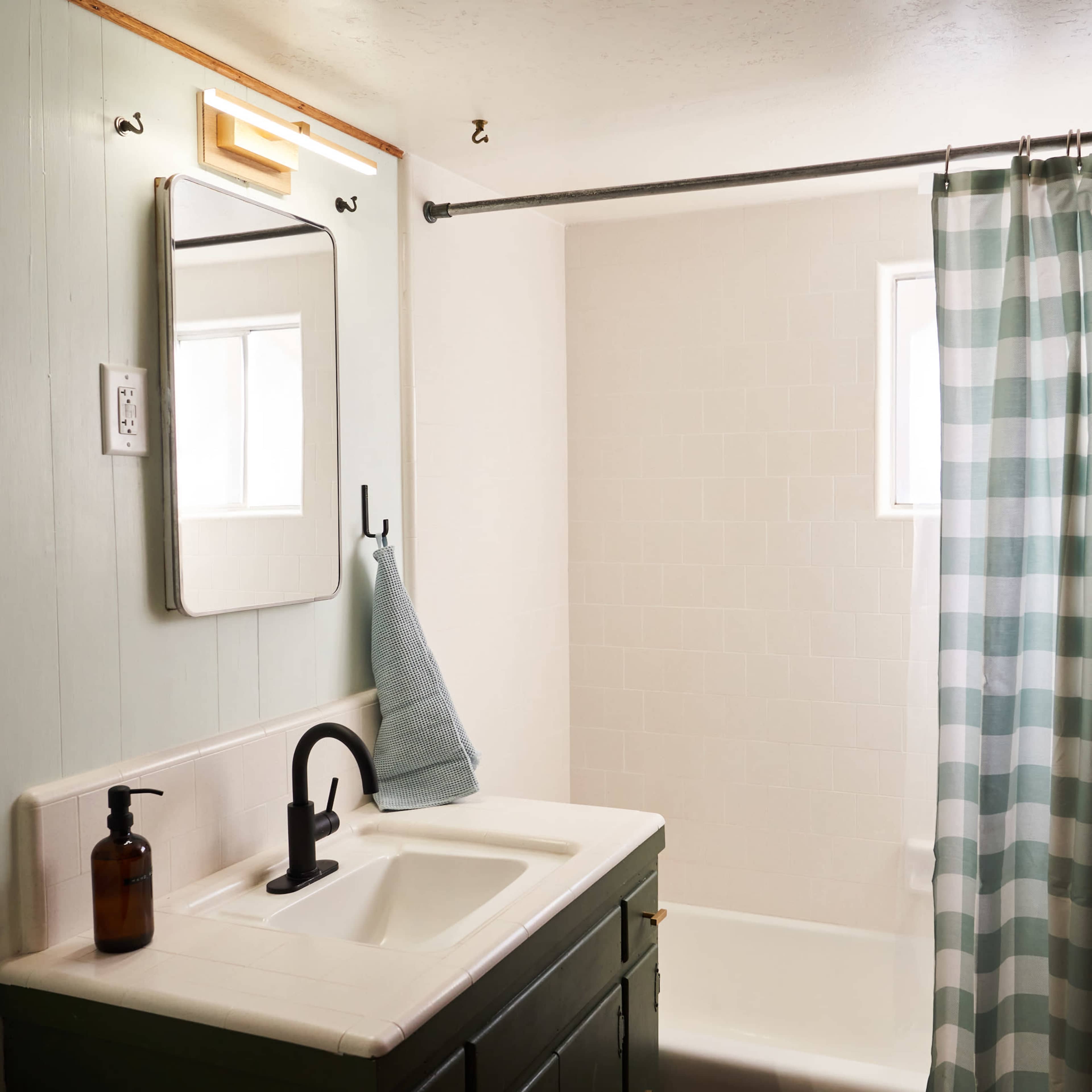 A bathroom with a sink, a mirror, a striped shower curtain, and a bathtub.