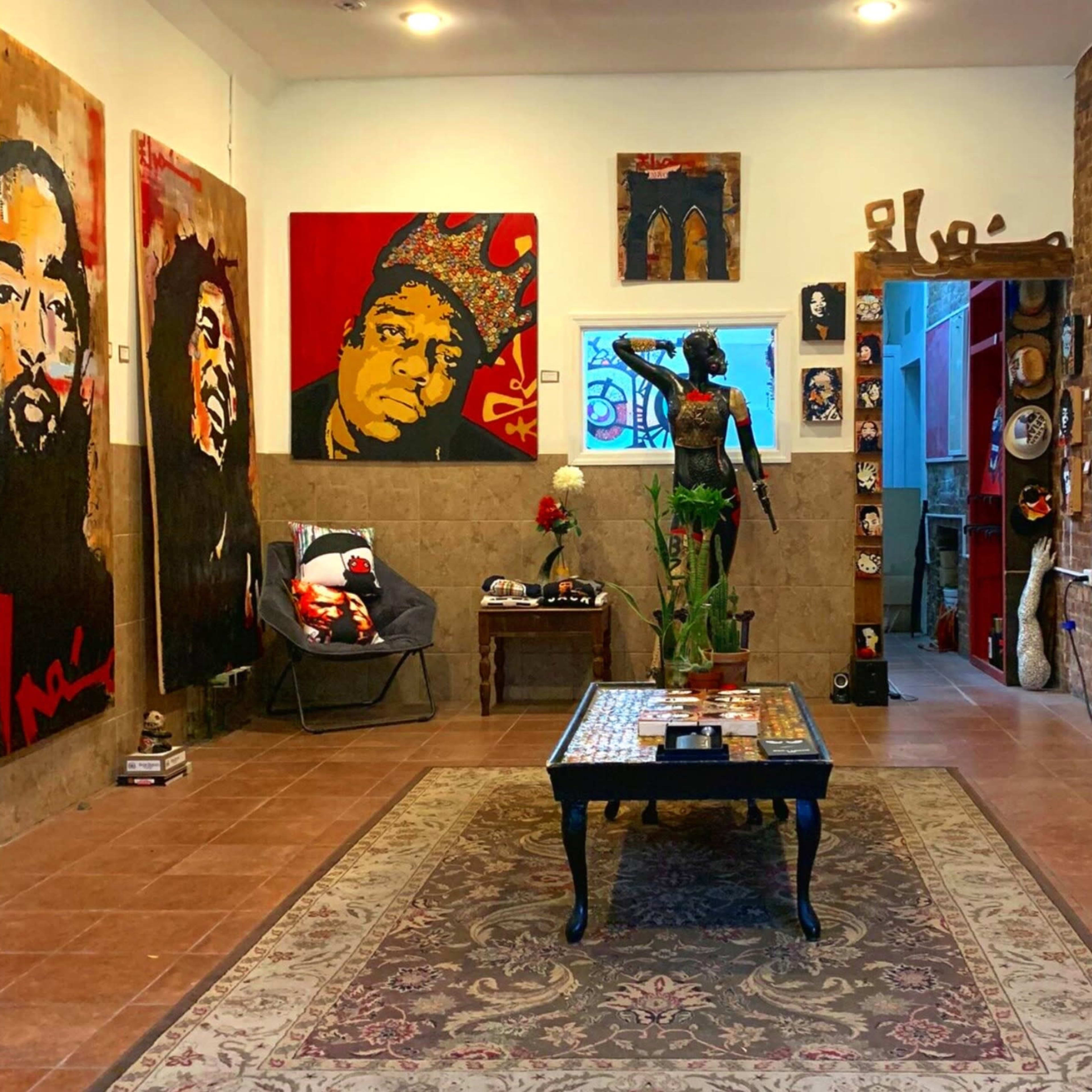 An art gallery interior featuring several large, colorful portraits on the walls, a decorative table in the center, and a statue in an alcove.