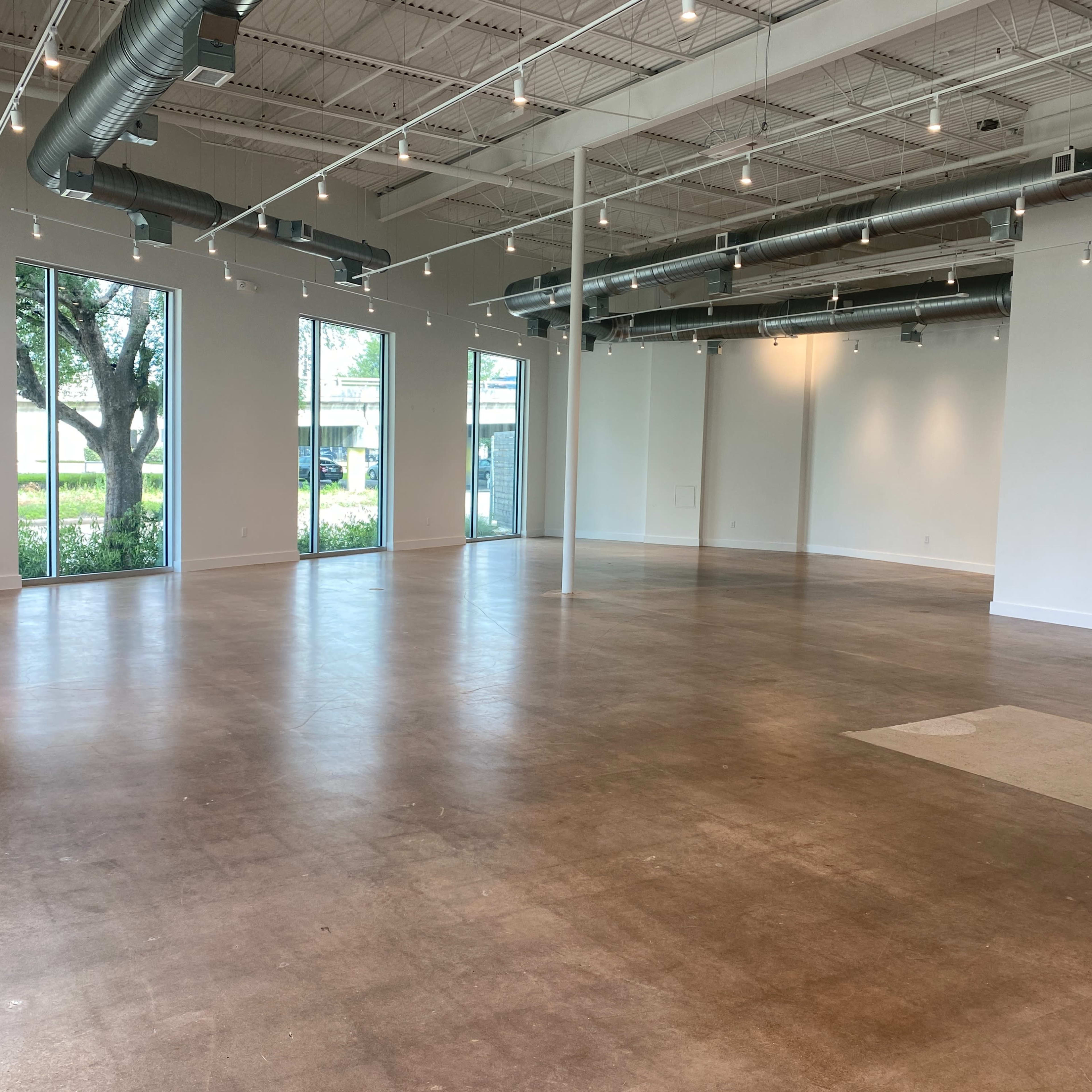 An empty commercial space features polished concrete floors and large windows allowing natural light to enter.