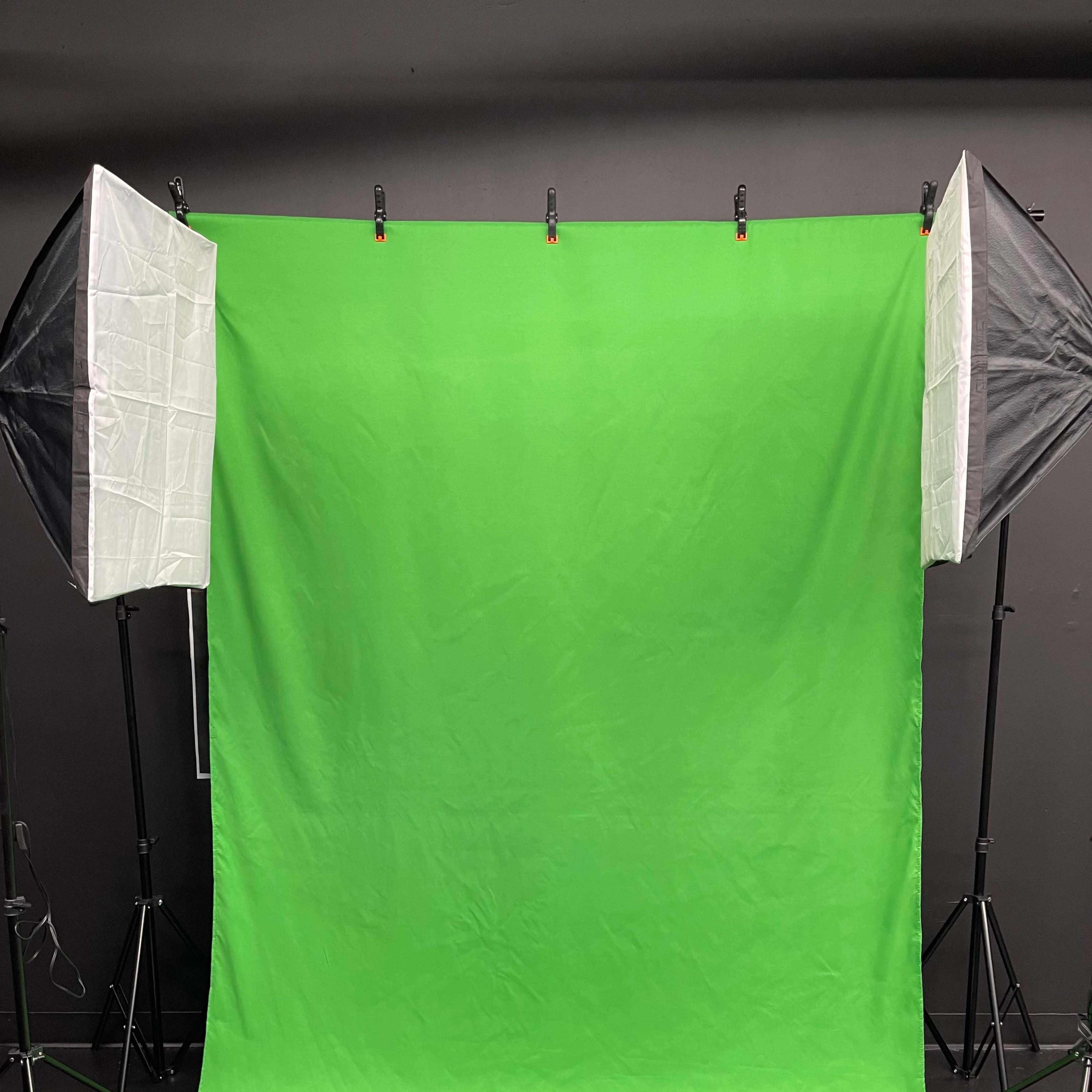 A green screen setup with two softbox lights on either side, positioned for photography or video production.