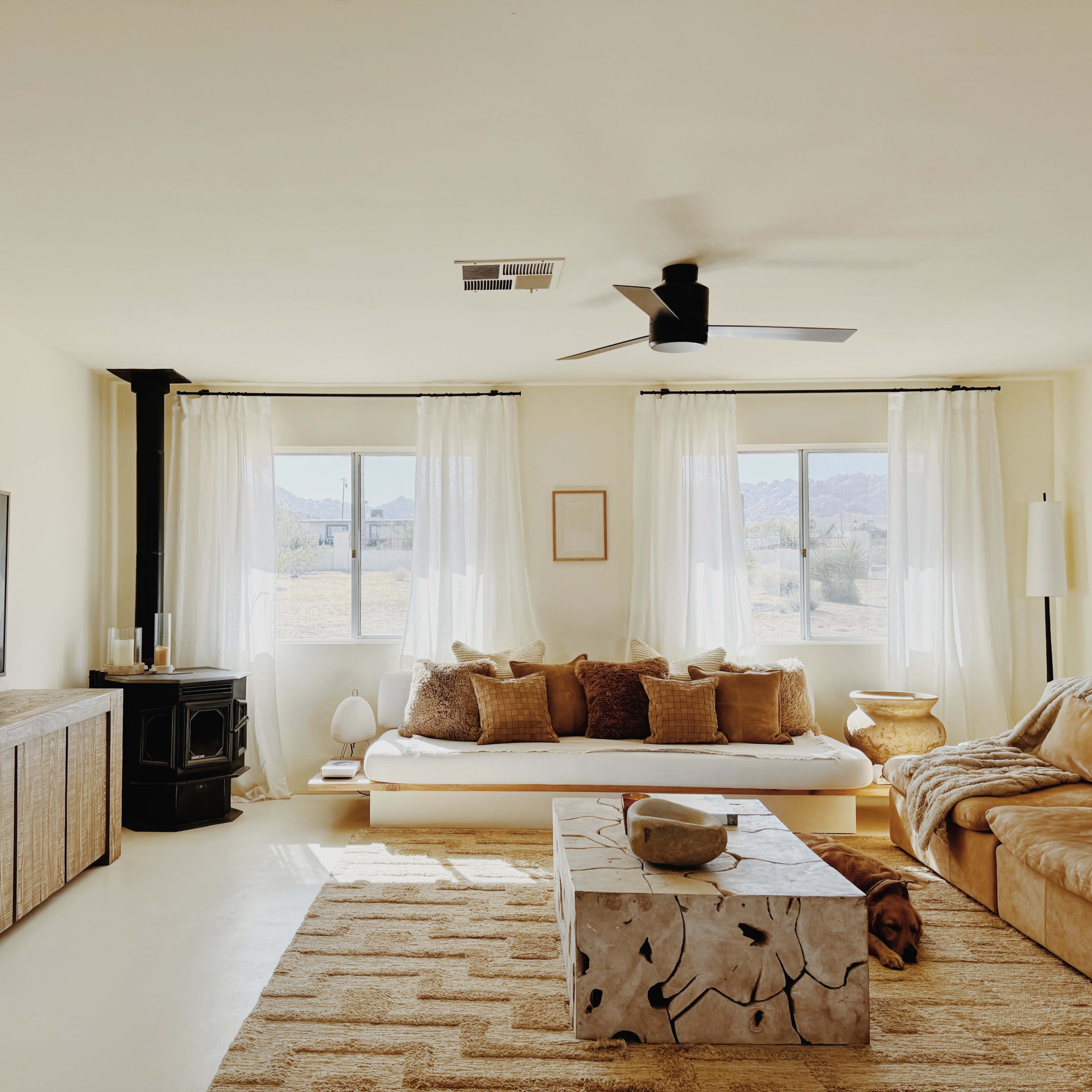 The living room features a sectional sofa and a wooden coffee table, with large windows allowing natural light to fill the space.