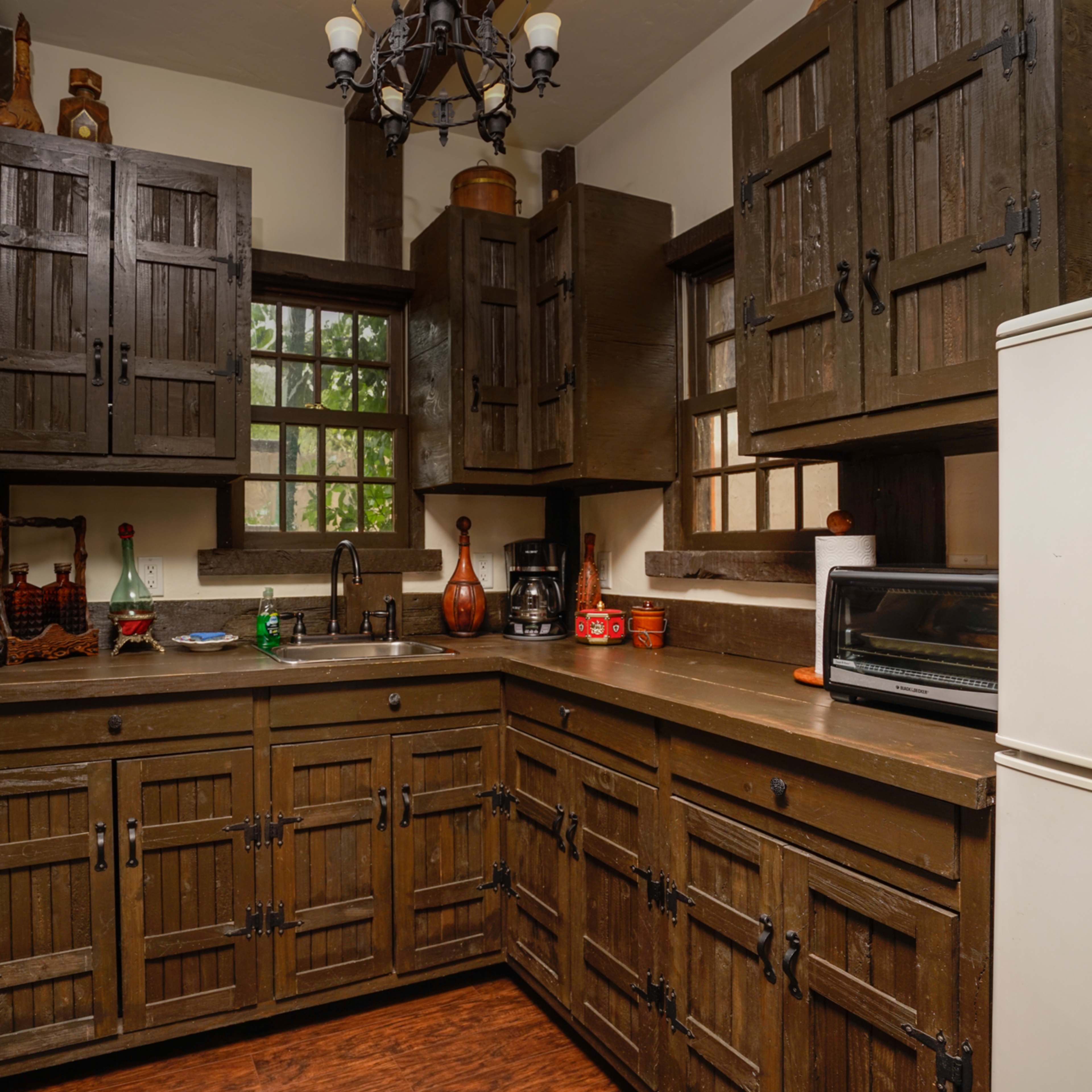 A wooden-paneled kitchen with dark cabinets, a countertop, and a sink, featuring a window and various kitchen appliances.