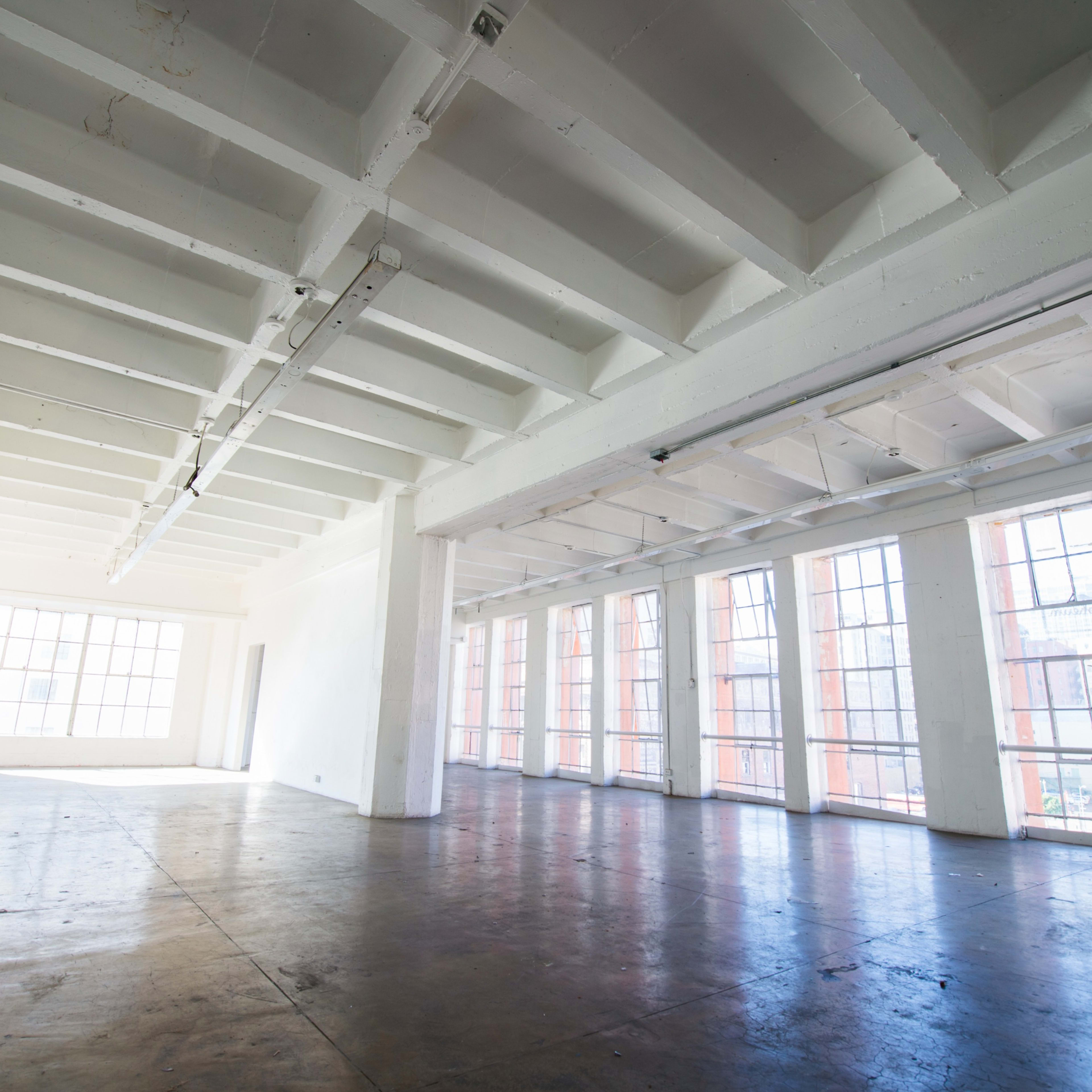 A spacious, empty room with large windows and a high ceiling.