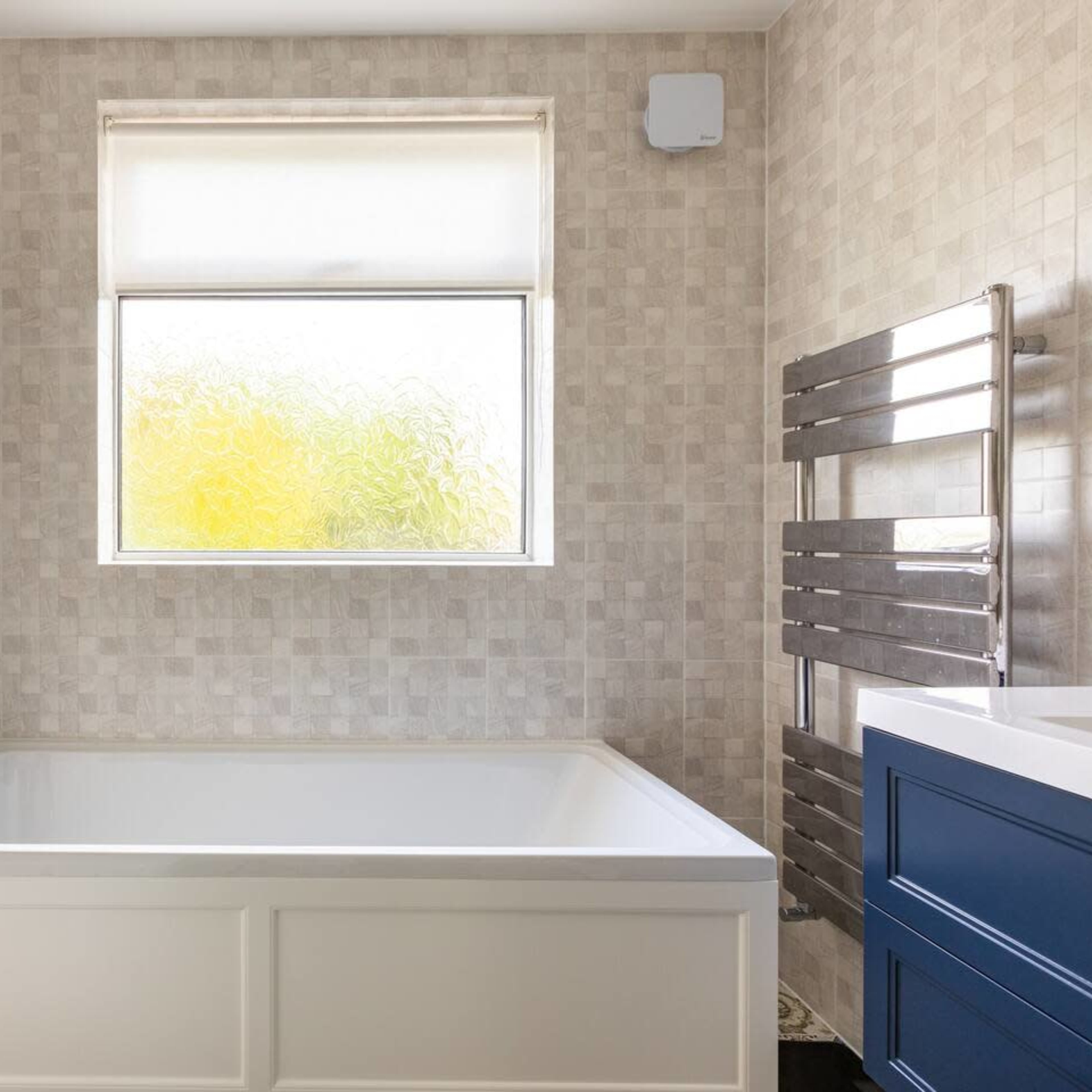 A modern bathroom featuring a white bathtub, a window with frosted glass, and tiled walls.