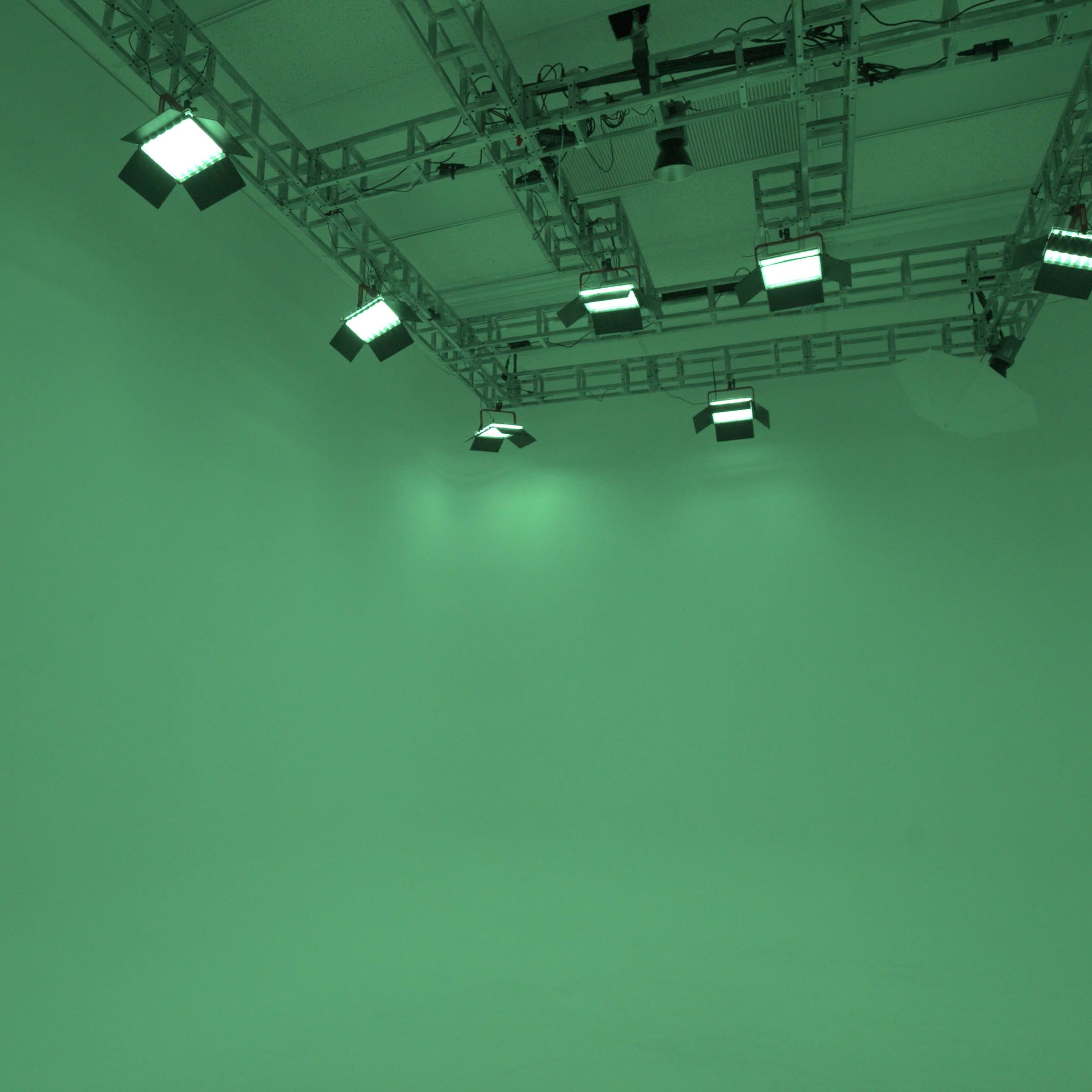 A green screen studio with overhead lighting fixtures.