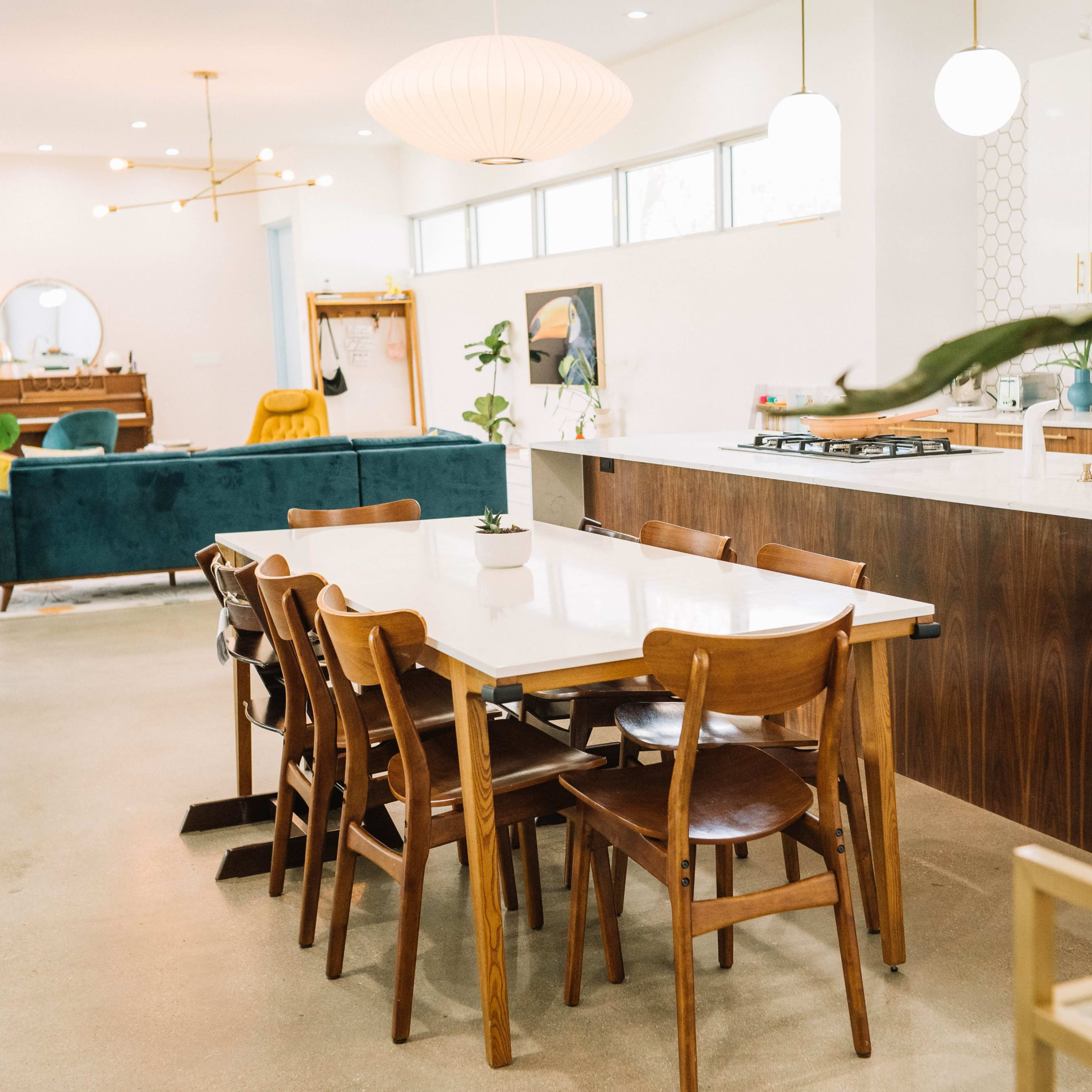 A spacious modern kitchen and dining area with a large table surrounded by wooden chairs, featuring an open layout and large windows.
