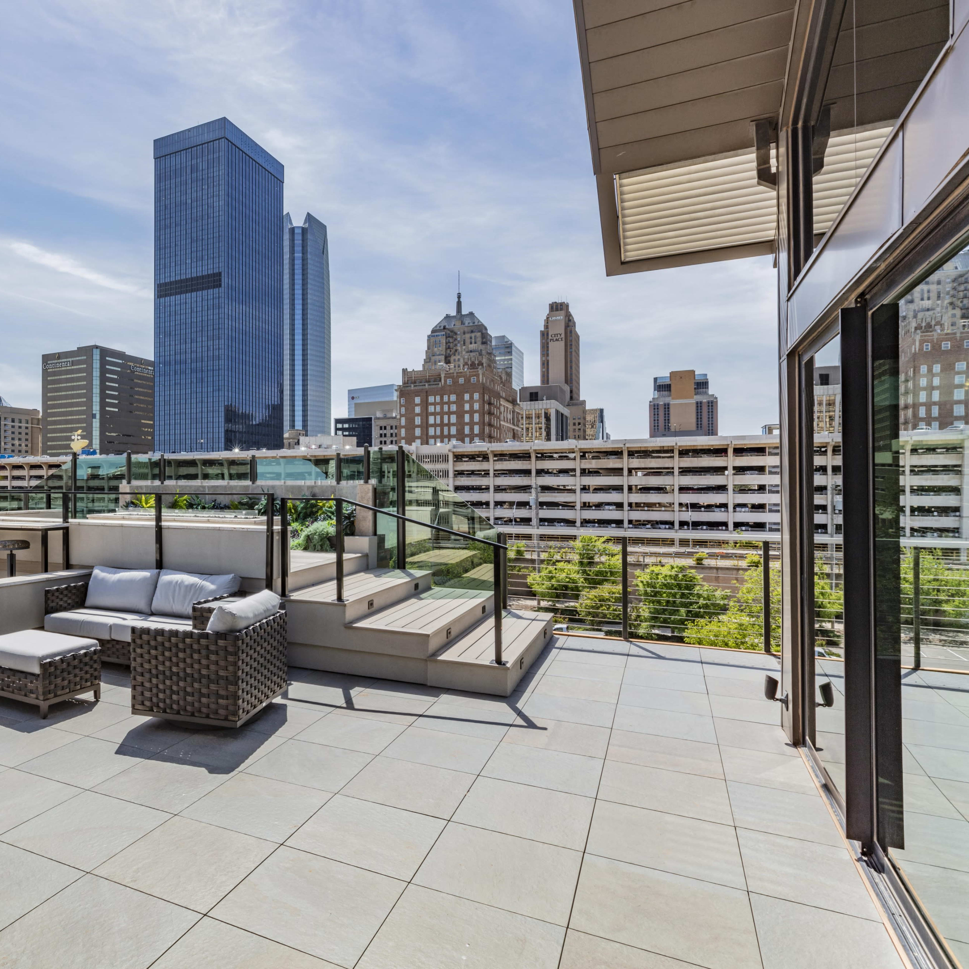 A terrace space features outdoor seating with a view of a city skyline and tall buildings.