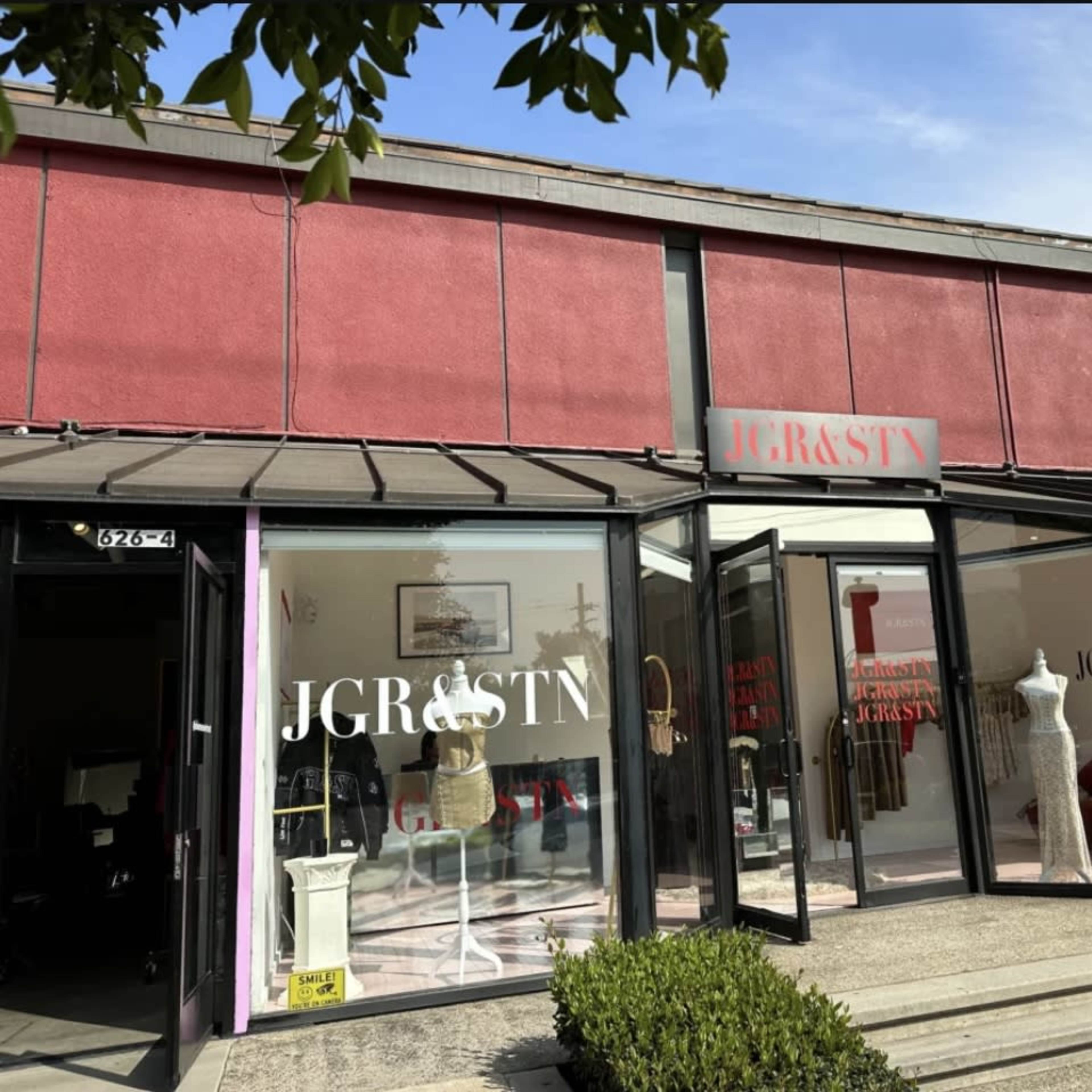 The exterior of a clothing store featuring large glass windows with the name "JGR&STN" prominently displayed.
