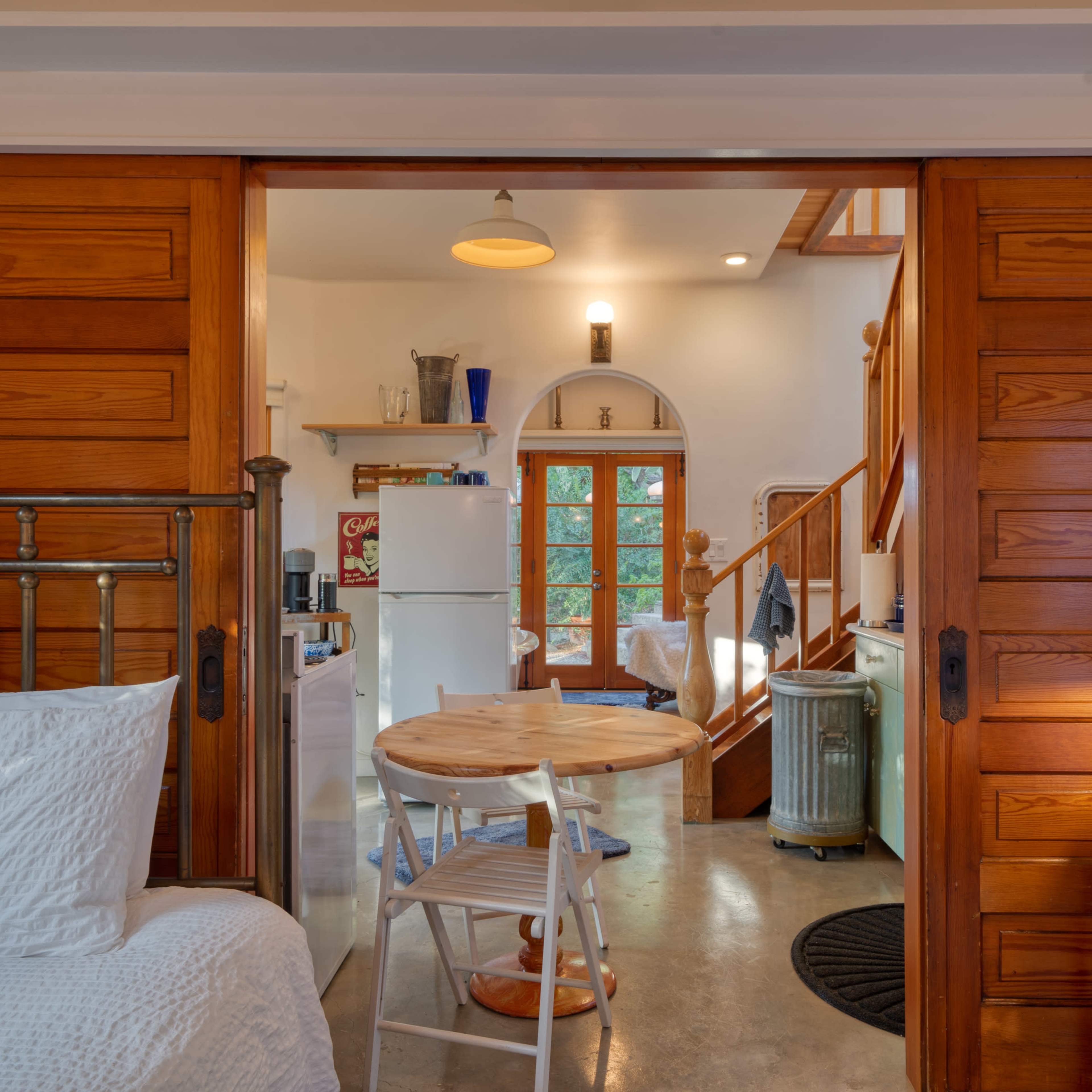 A view shows a cozy interior space with wooden doors leading to a kitchen area and a staircase.