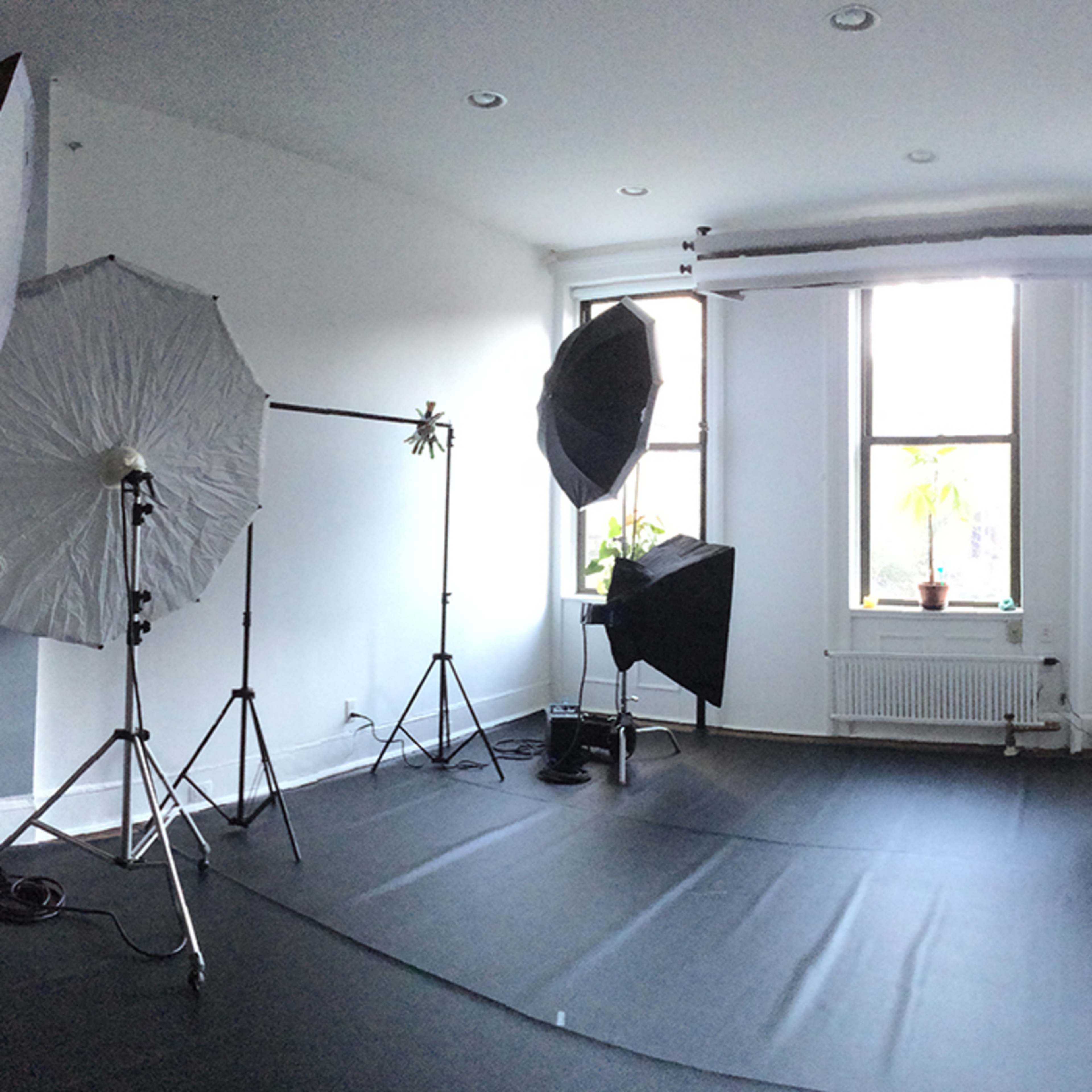 A photography studio set up with multiple light sources and softboxes arranged around a dark seamless backdrop.