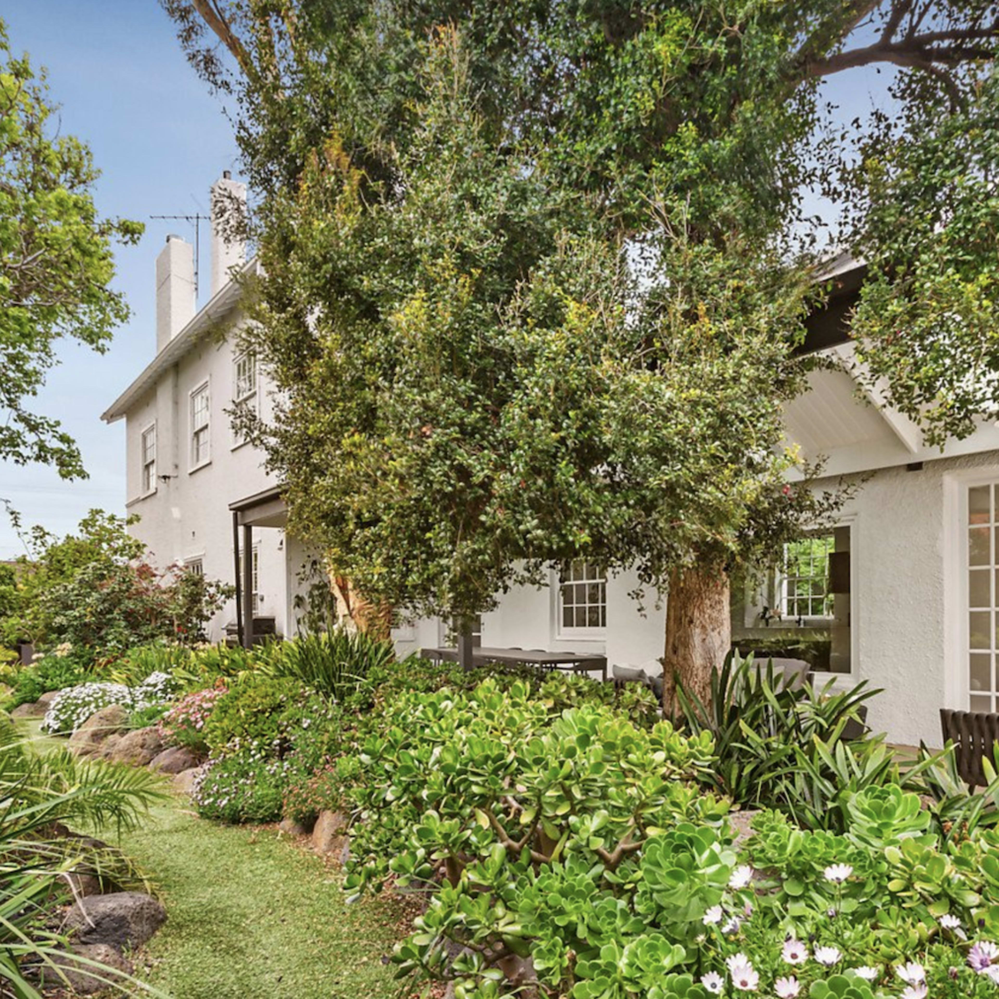 A well-maintained garden alongside a two-story house with large windows and a patio area.