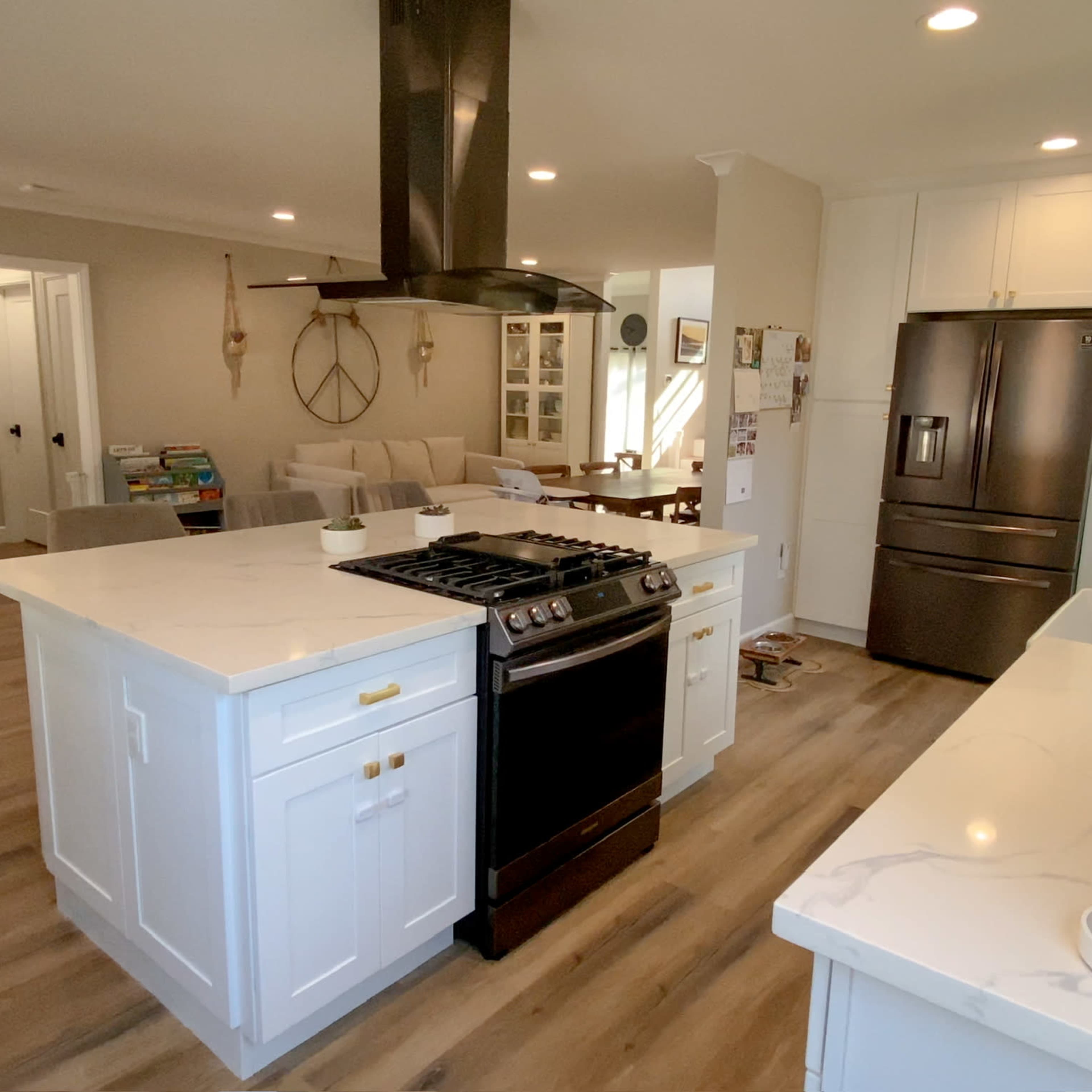 A modern kitchen featuring a central island with a stovetop, stainless steel appliances, and white cabinetry.