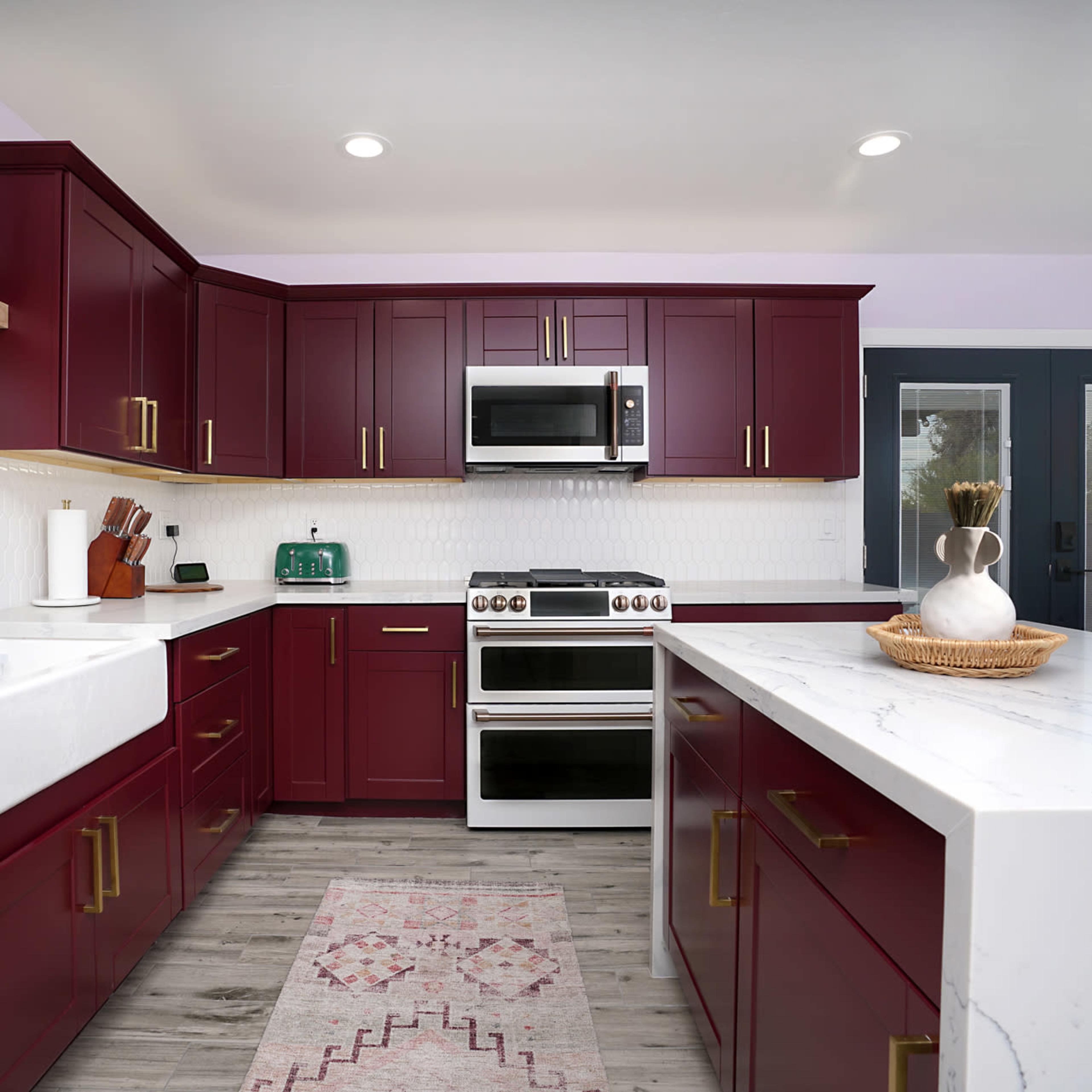 The kitchen features burgundy cabinets, stainless steel appliances, and a white countertop with a farmhouse sink.