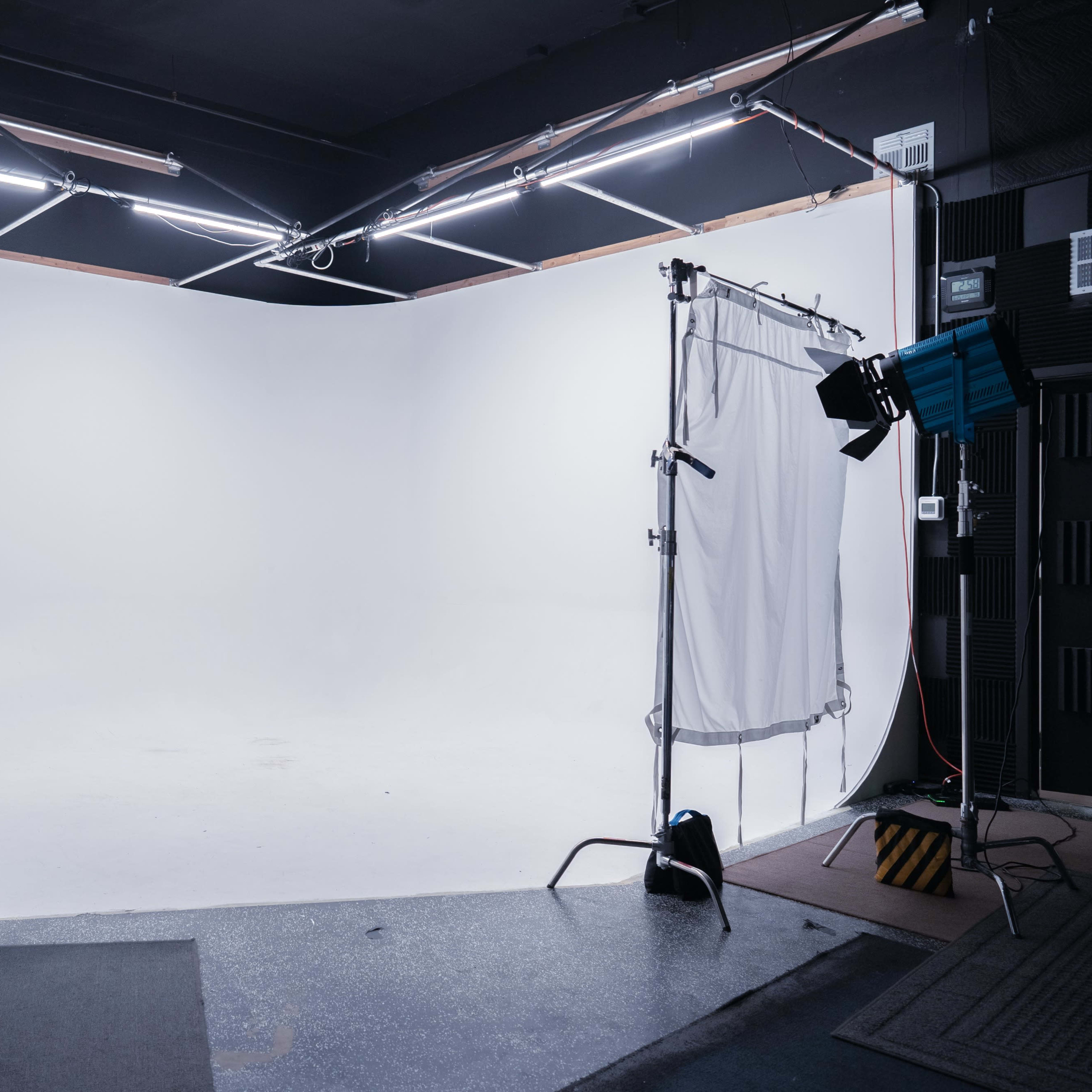 A photography studio with a large white backdrop and various lighting equipment set up on tripods.
