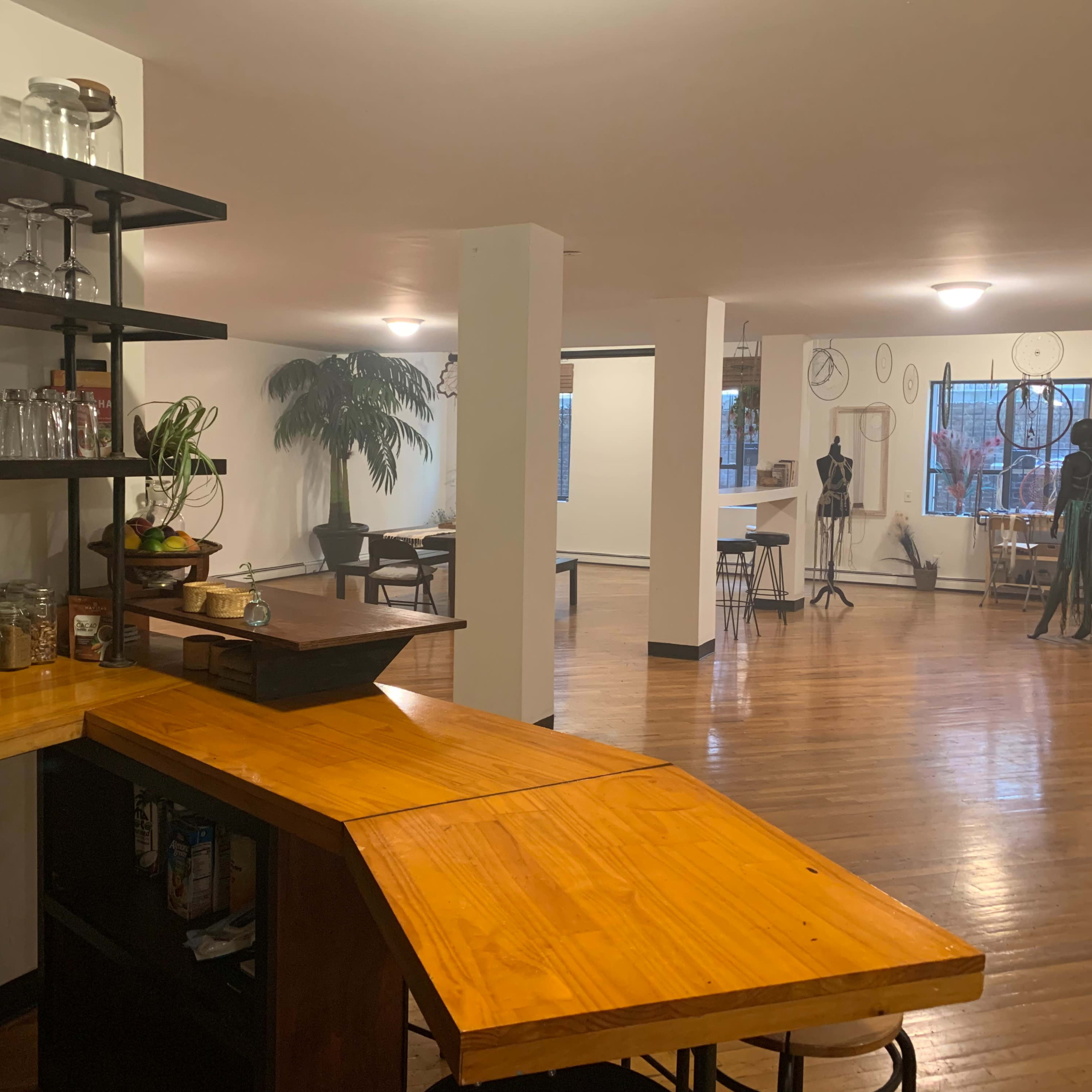 A spacious interior with a wooden bar area, glassware, a plant, and several mannequins positioned throughout the open room.