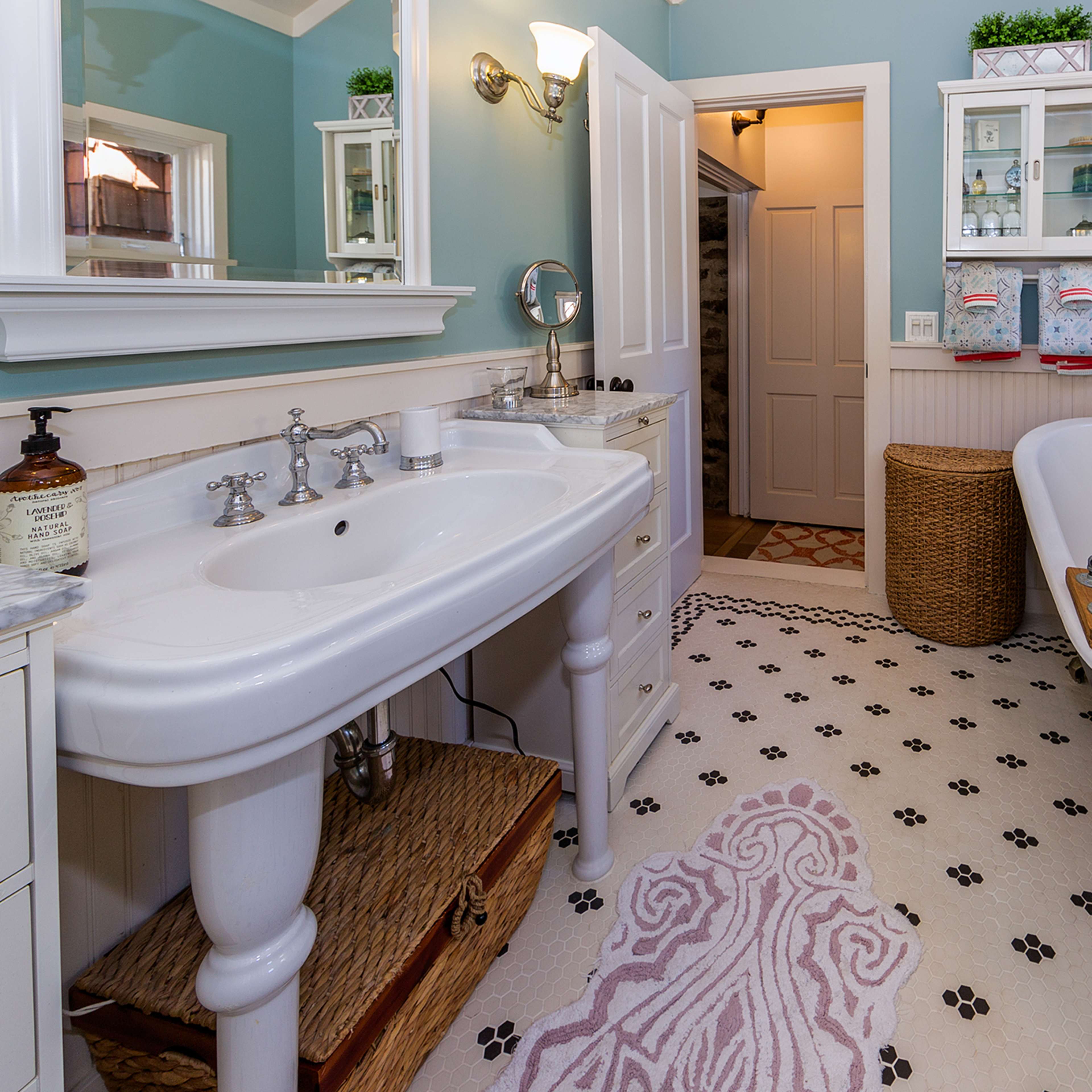 A bathroom featuring a freestanding bathtub, a double sink vanity, and pet-themed flooring.