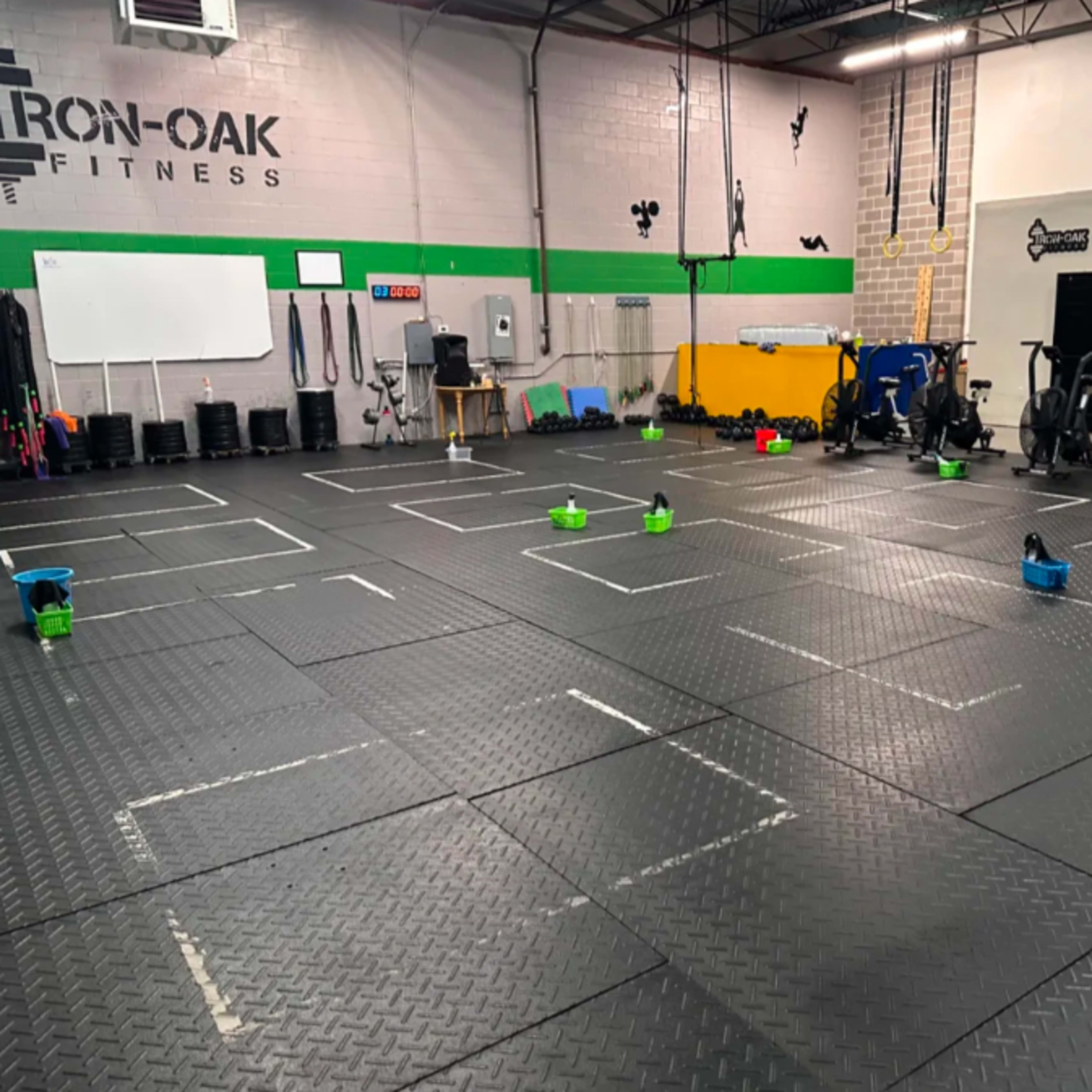 A functional fitness gym with marked squares on the floor and various exercise equipment along the walls.