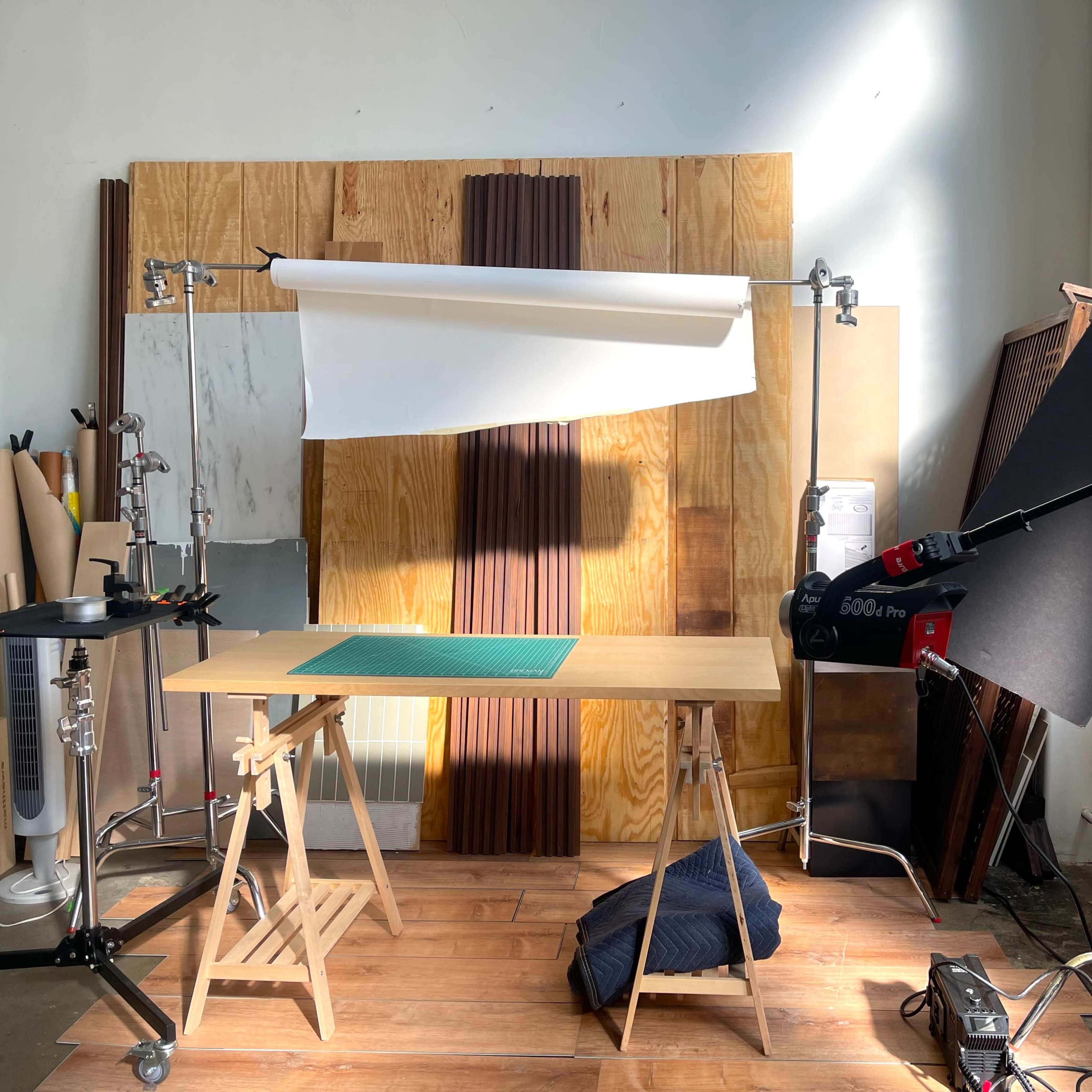 A photography setup with a wooden table, backdrop, and lighting equipment in a well-lit studio space.